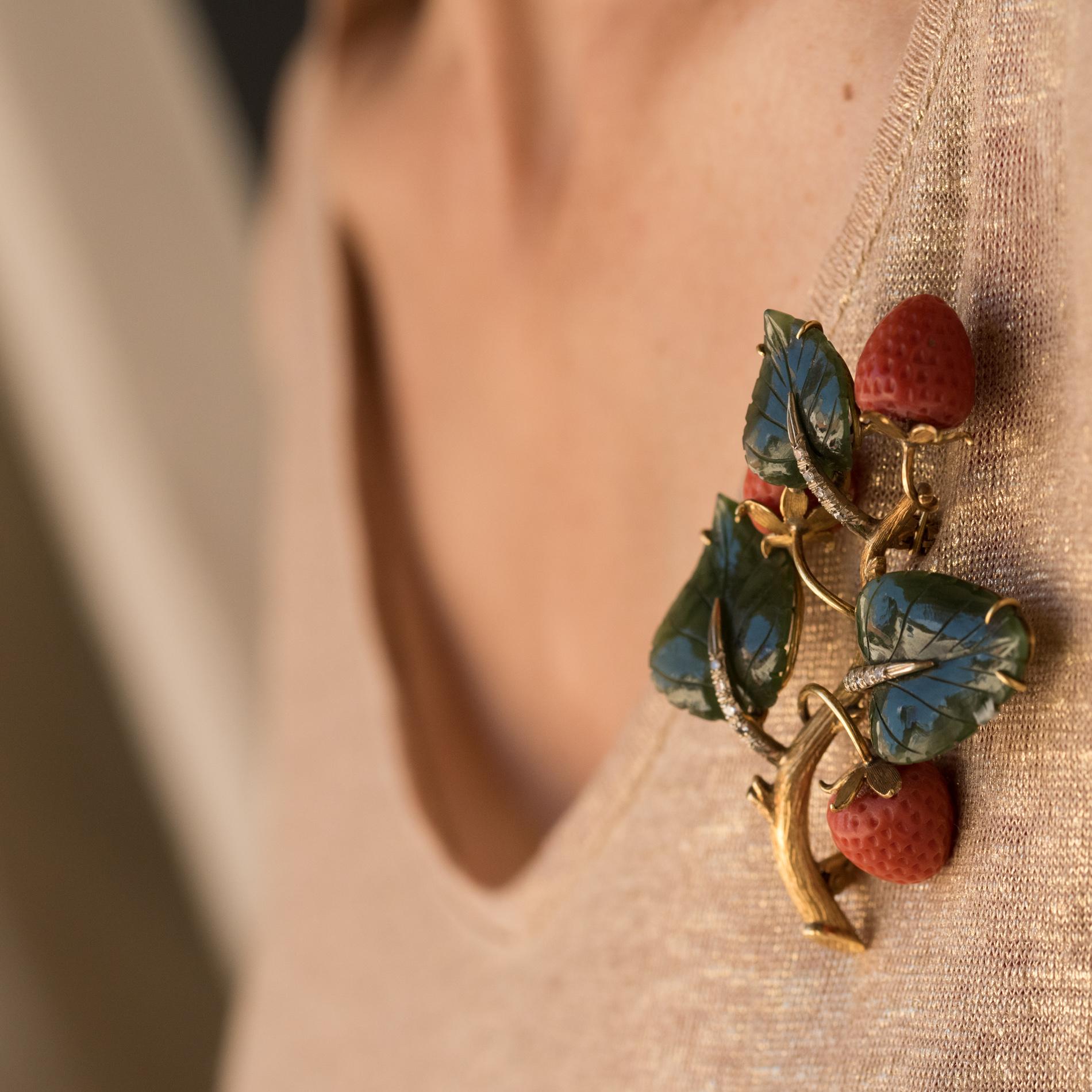 Brosche aus 18 Karat Gelbgold:: Eulenpunze. 
Diese antike Brosche stellt einen Zweig einer Erdbeerpflanze mit eingravierten Jadeblättern dar. Die zentrale Ader ist mit Diamanten besetzt und die Erdbeeren sind aus geschnitzter Koralle. 
Gesamtgewicht