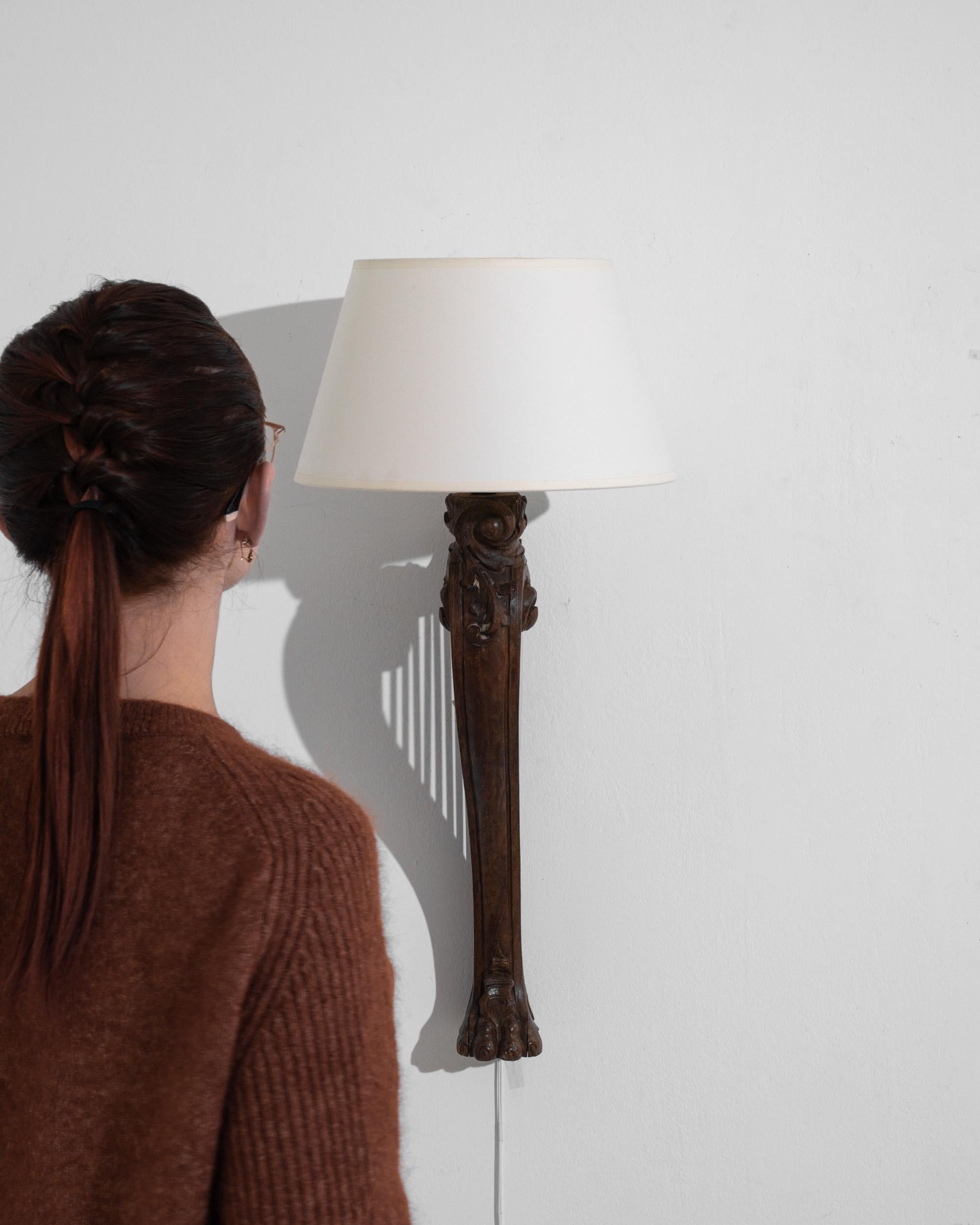 This carved wooden wall sconce from turn of the century France brings Beaux Arts lyricism to your space. Viewed from the front, the sconce resembles an elephant foot, blossoming into a leafy flourish; viewed from the side, the graceful bow of a harp