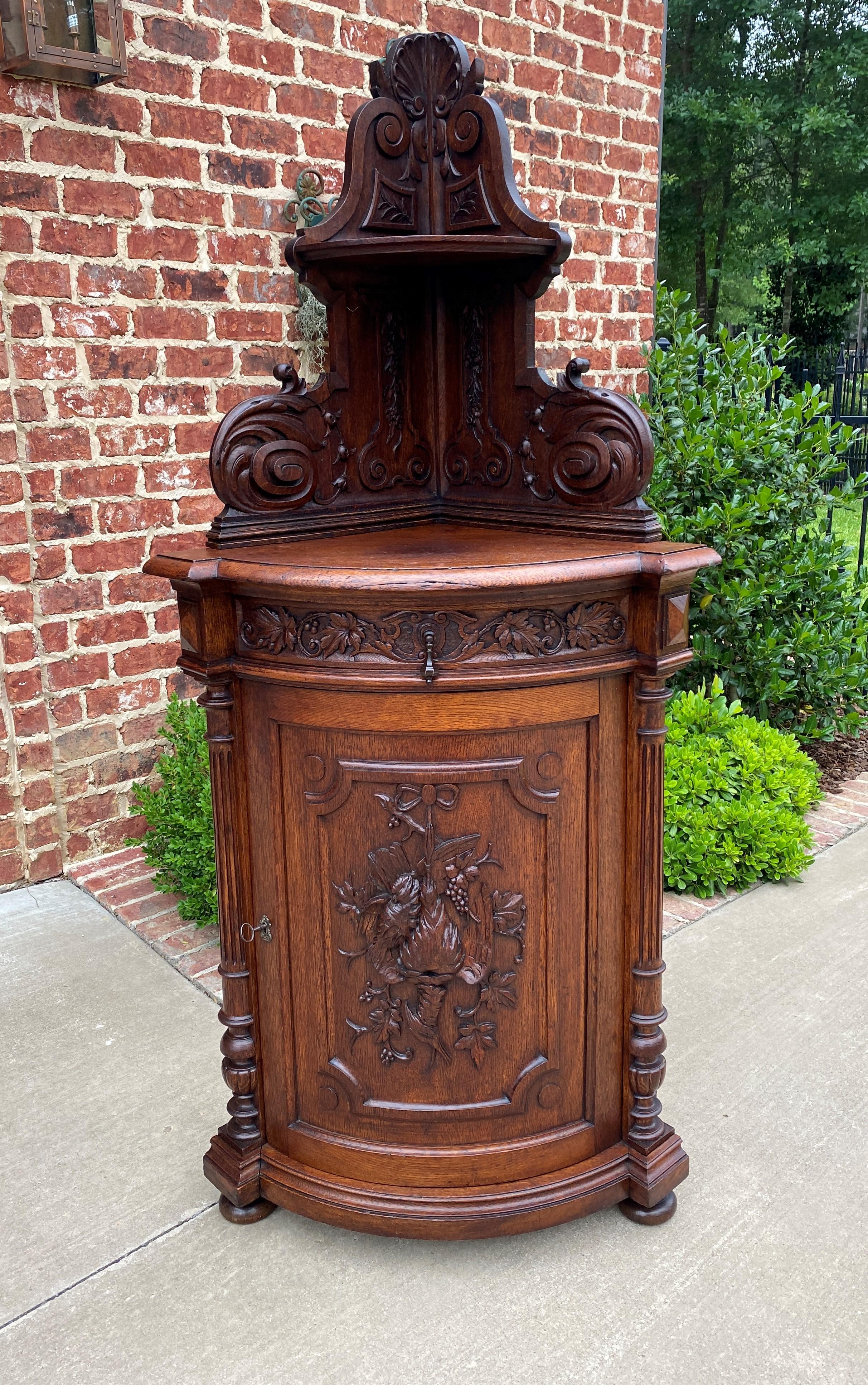 Beautifully carved Antique French oak black forest corner cabinet, bookcase, display or storage cabinet ~~c. 1880s.

Full of classic French flair~~beautifully carved ribbon and game birds on the lower door~~fluted columns~~corner cabinets are one