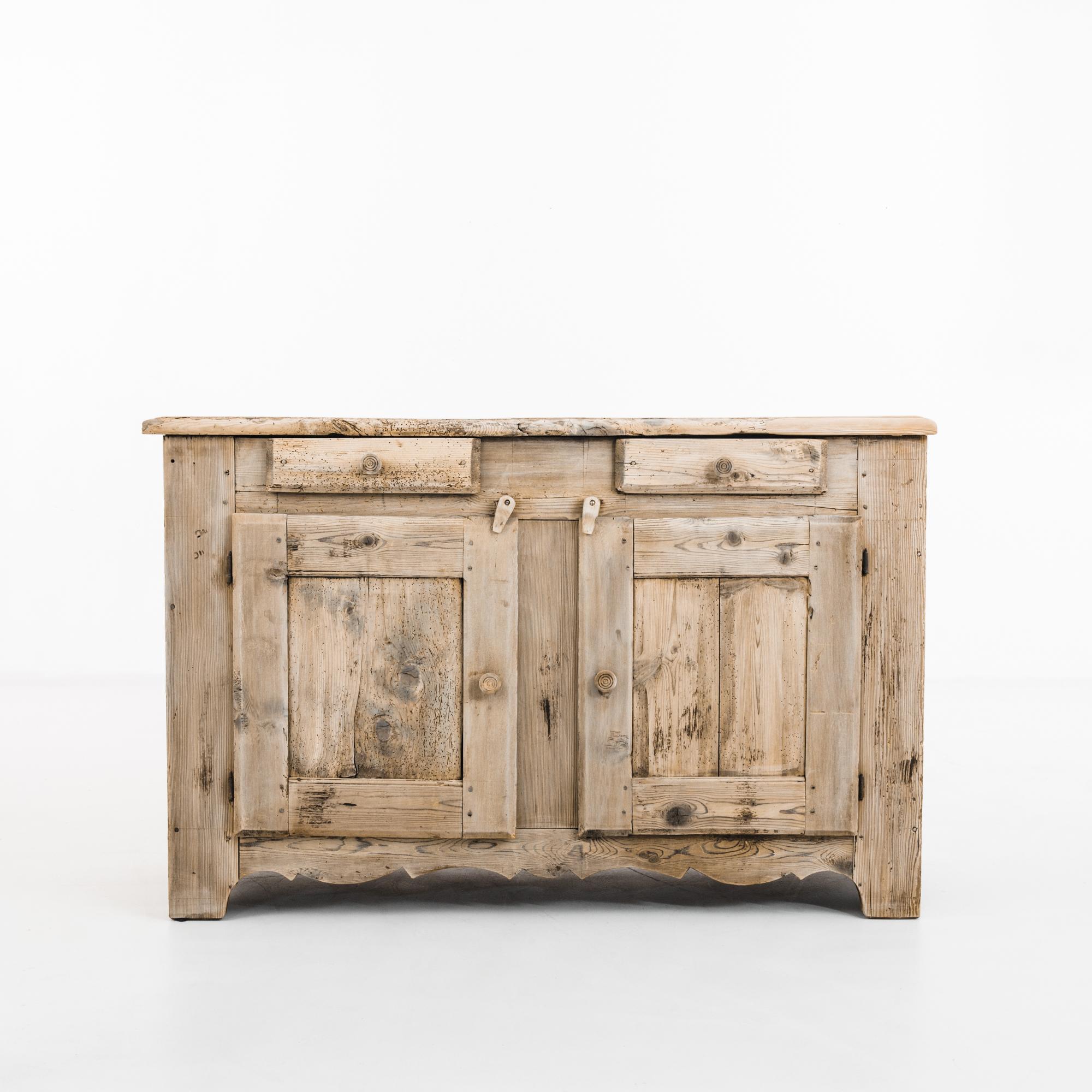 Made in France, this antique bleached oak buffet features an angular structure softened by the contoured apron and circular pulls. It consists of two drawers and two shelves in the storage compartment below, with double doors that can be secured