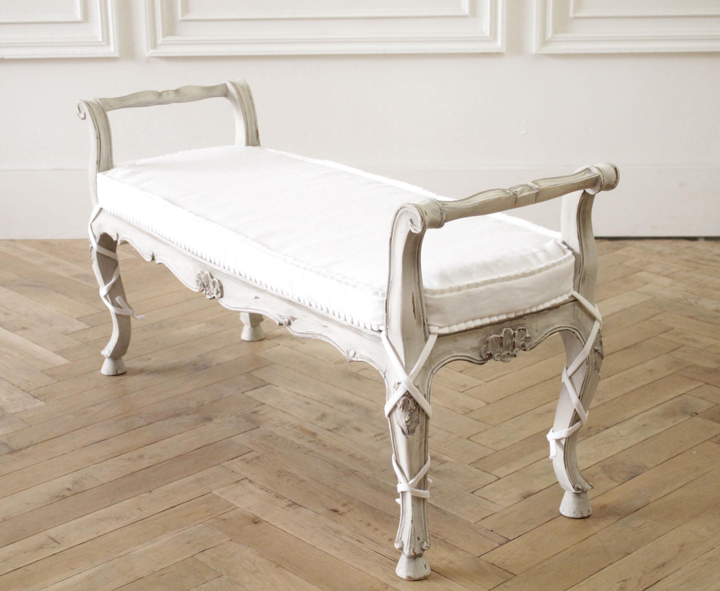 Antique French country cane bench with organic linen hand pleated ruffle cushion.
This pretty bench is painted in our soft oyster finish, with a gray glazed antique patina. Soft distressed edges, and cane seat. This bench is solid and sturdy ready