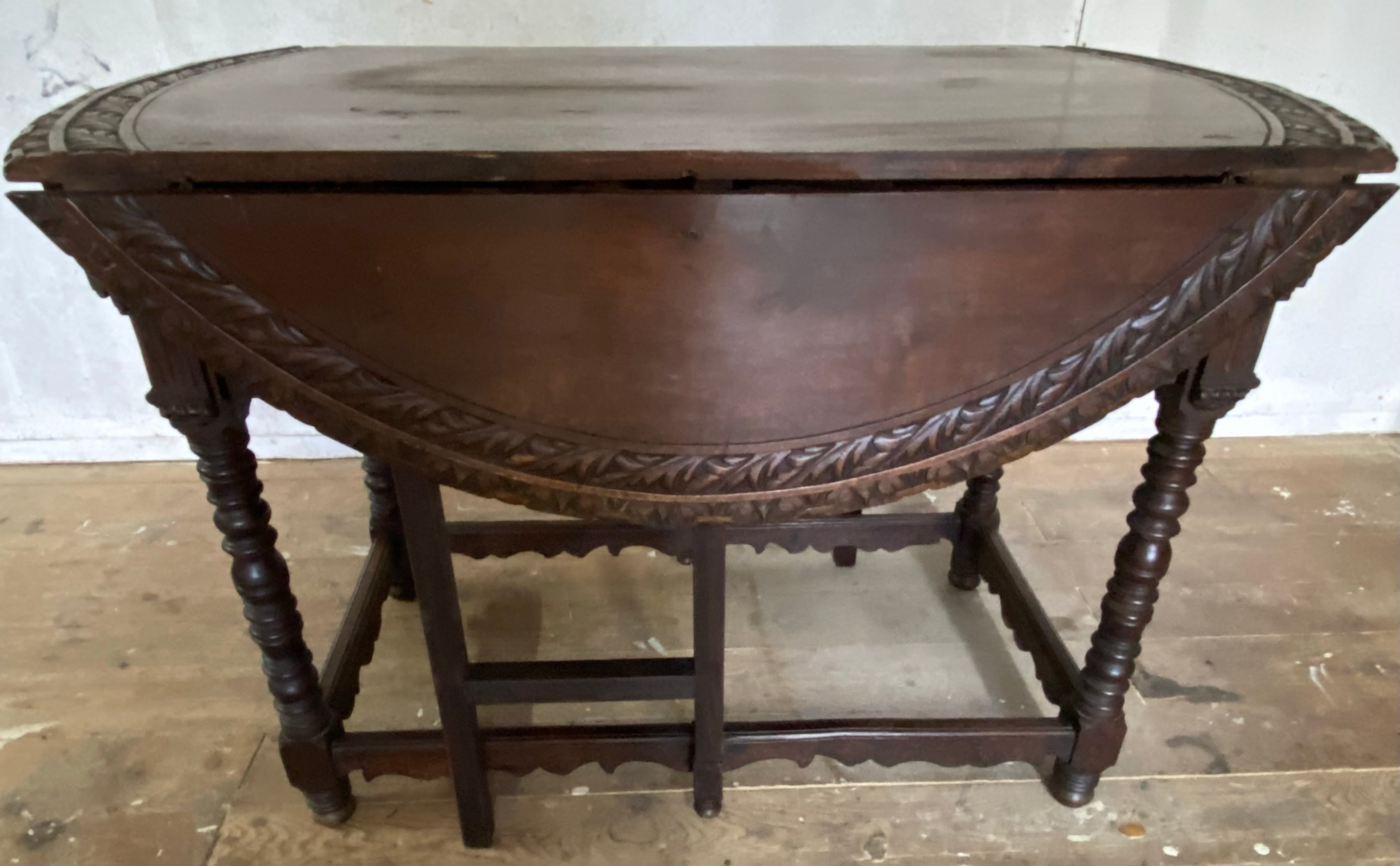 An unusual 19th Century antique, finely carved decorated drop leaf table with turned legs and beautiful aged patina.  The sides of the circular table fold down, allowing it to be easily stored when not in use. or use as sofa table when space is
