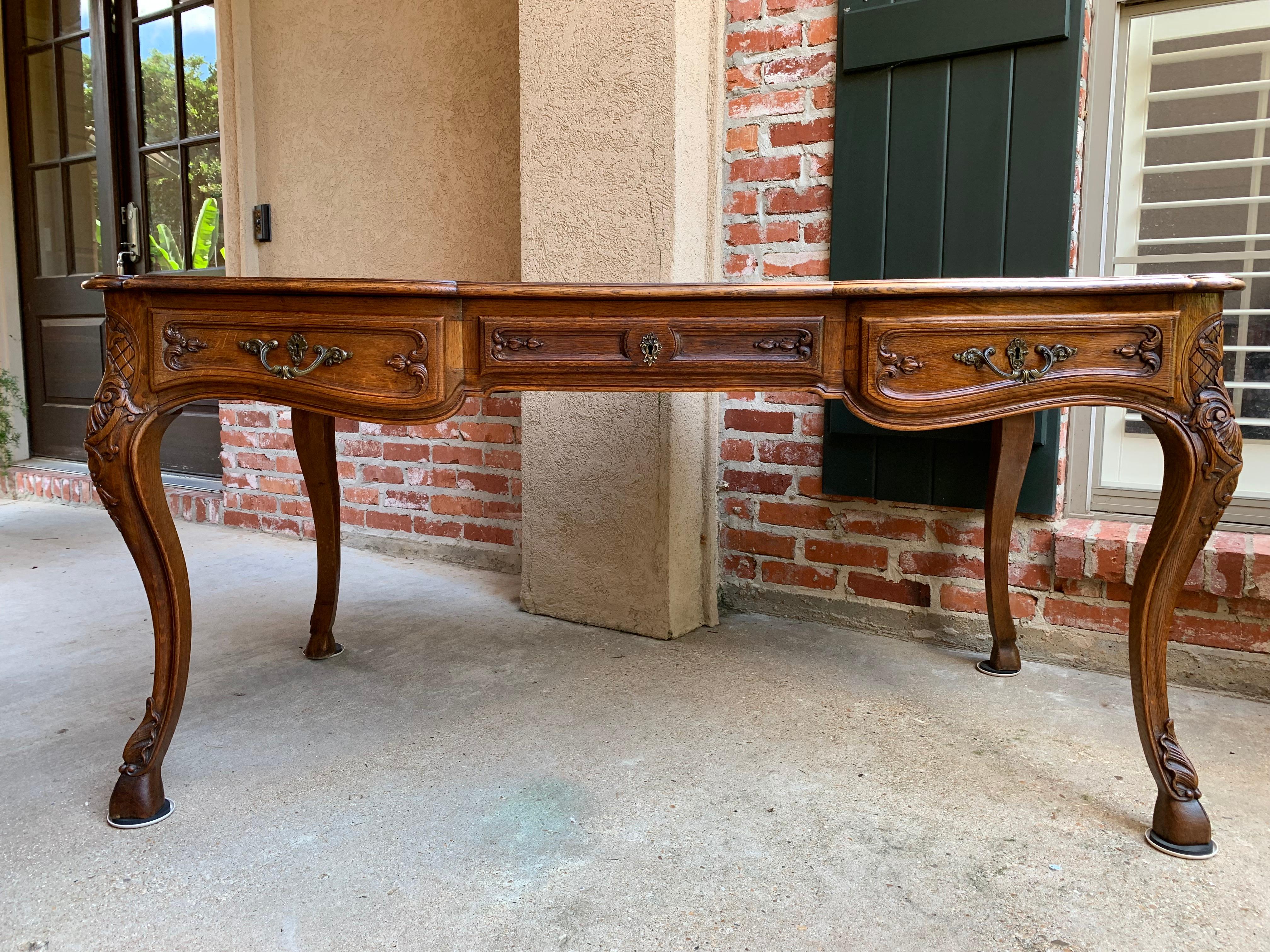 Direct from France, a beautiful antique French carved oak writing or library desk, in a large 5 ft. size!~ 
~Such a gorgeous silhouette with it’s heavily carved cabriole legs and ram’s hoof feet.
~Three carved and paneled serpentine drawers across