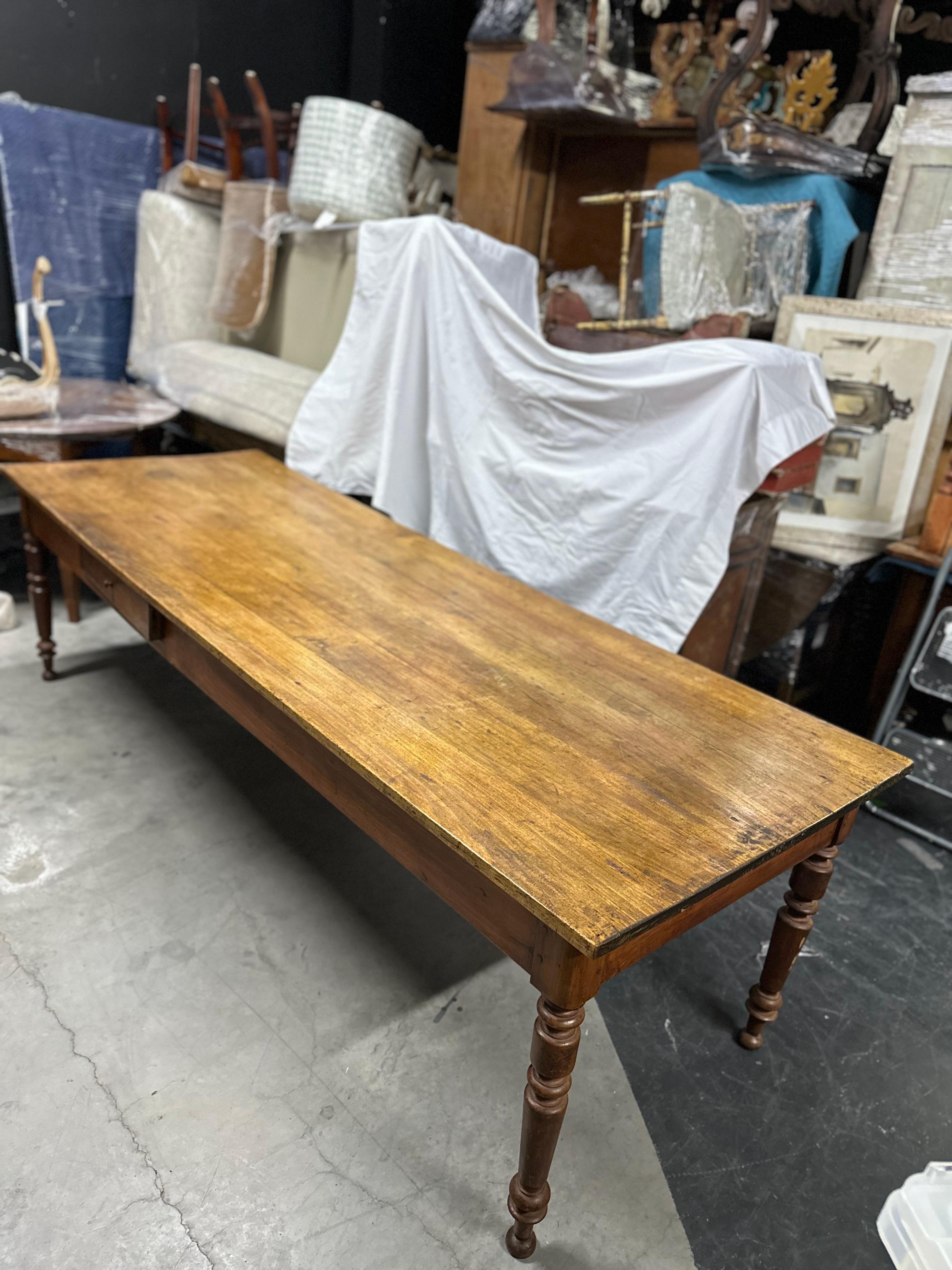 This Antique French Country Farm Dining Table exudes rustic charm and timeless appeal. Crafted with meticulous attention to detail, it features a plank top that showcases the natural beauty of the wood grain. The turned legs add a touch of elegance
