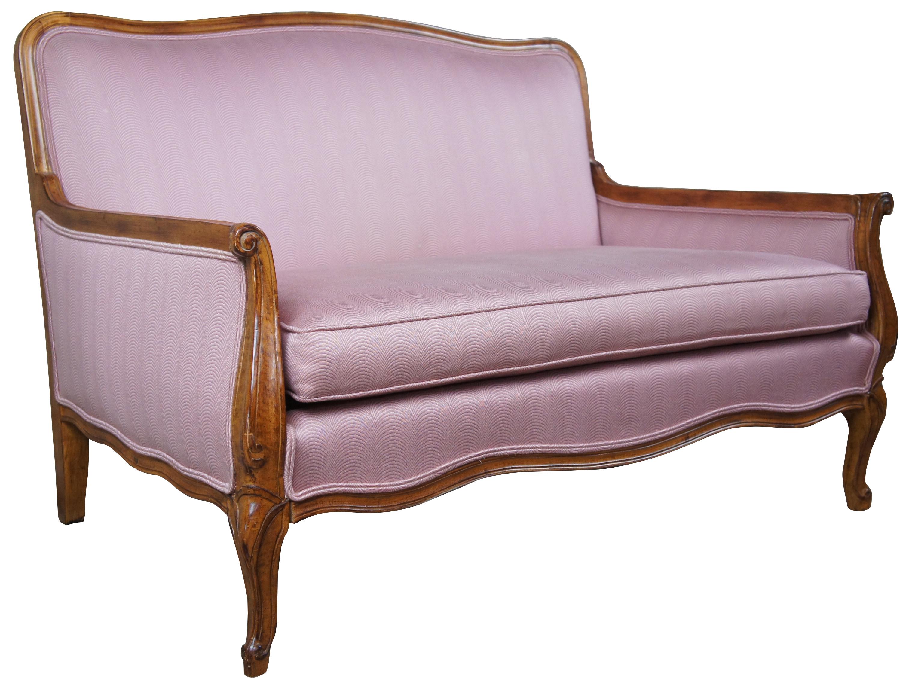 20th century country French camelback settee. Made from walnut scrolled and flared arms. Upholstered in pink. Measure: 46