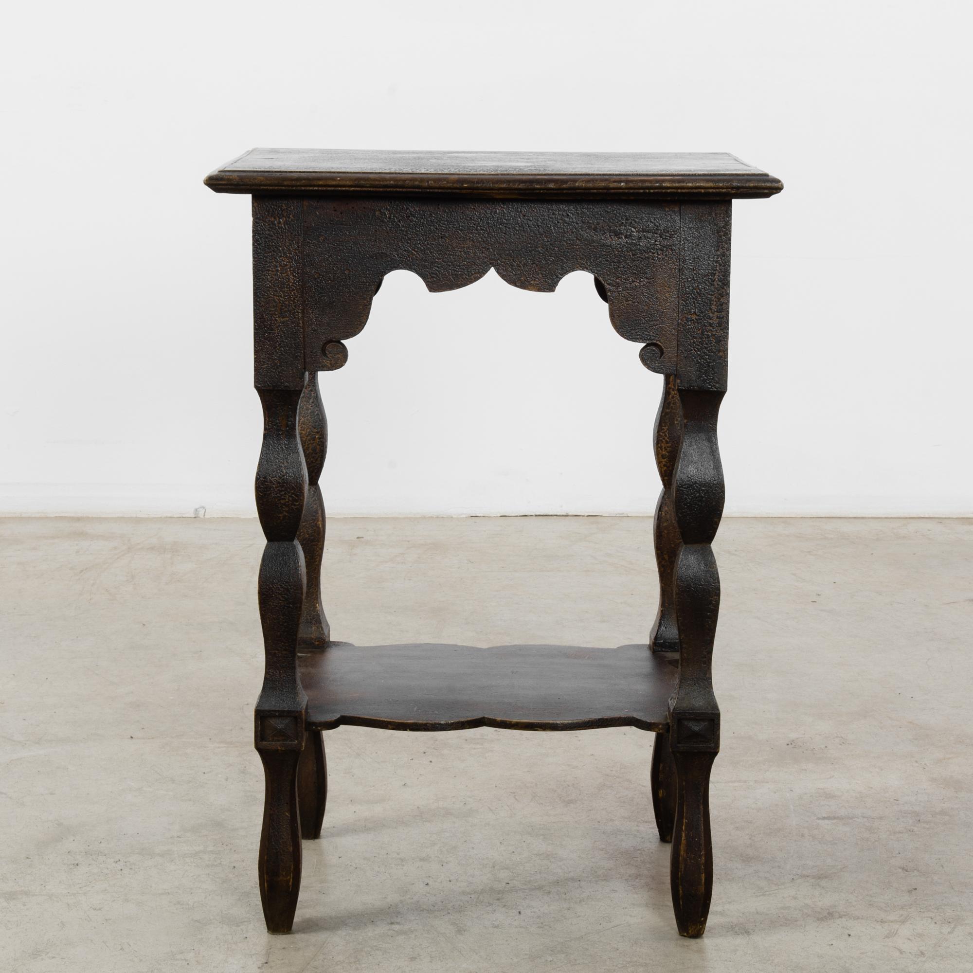 A side table from France, produced circa 1900. This little side table is bold, brown, and beautiful with its original patination raising up to create a textured surface. Features a lower shelf, nestled between legs of carefully constructed tapered