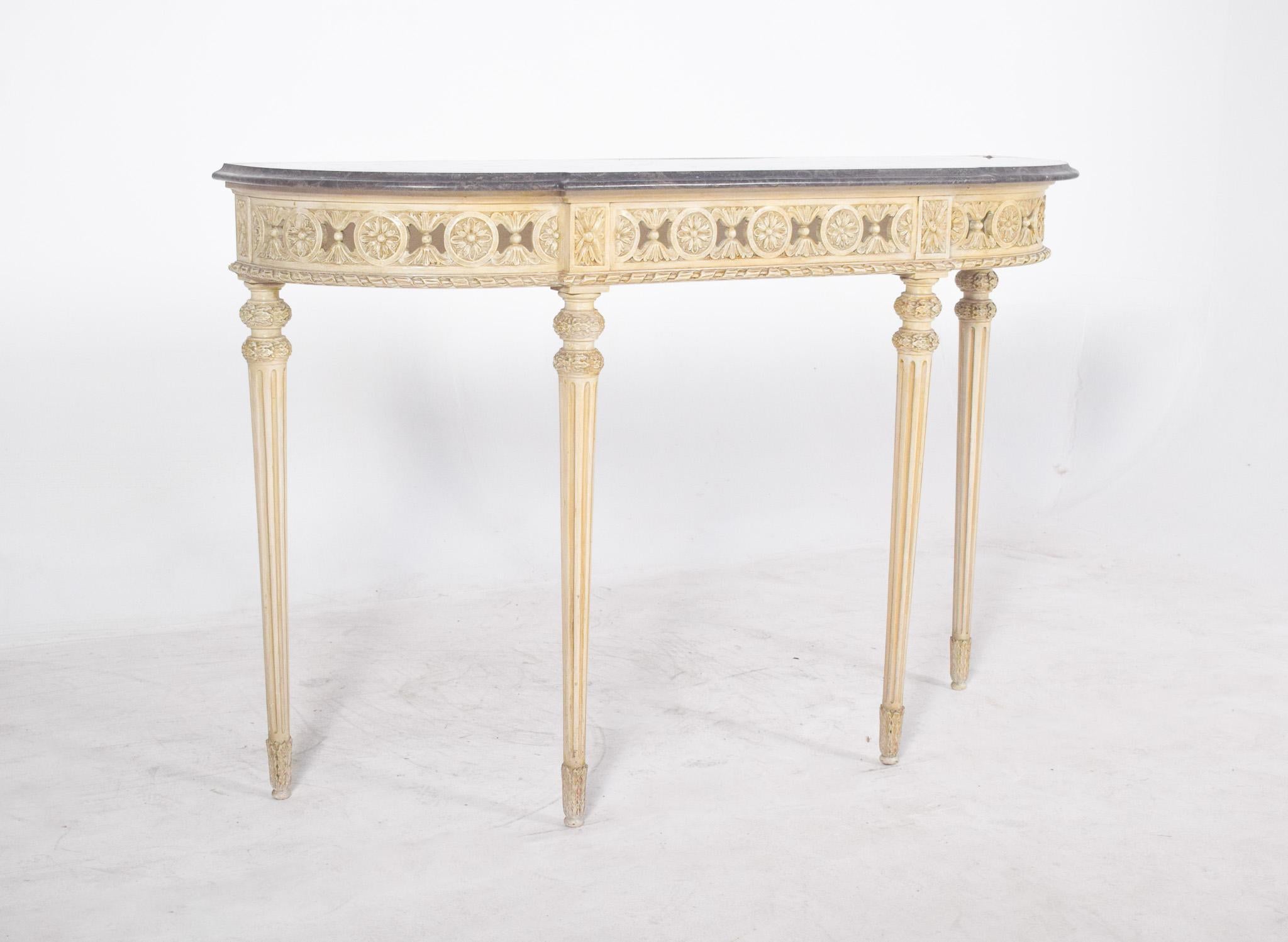 Credenza with marble top. With its delicate decoration, it evokes the refinement of French neoclassical furniture. The carved wooden structure is painted in a light ivory colour, with finely carved relief details along the frieze, where floral and