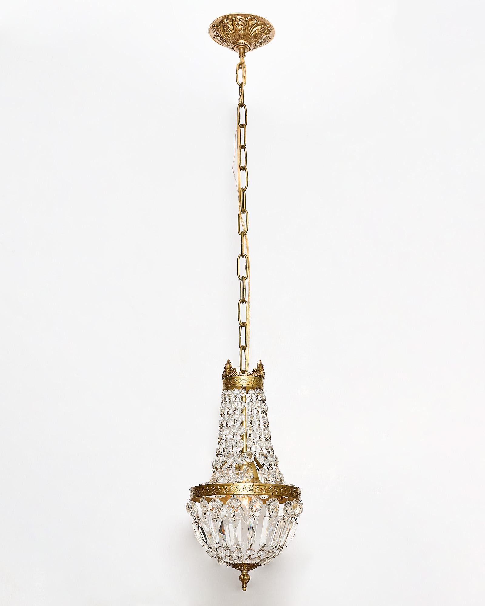 Chandelier, French, in the Louis XVI style. The neoclassic fixture is made of finely cast gilded bronze and features an array of cut crystal pendants and “cabochons”. It has been newly wired to fit US standards.