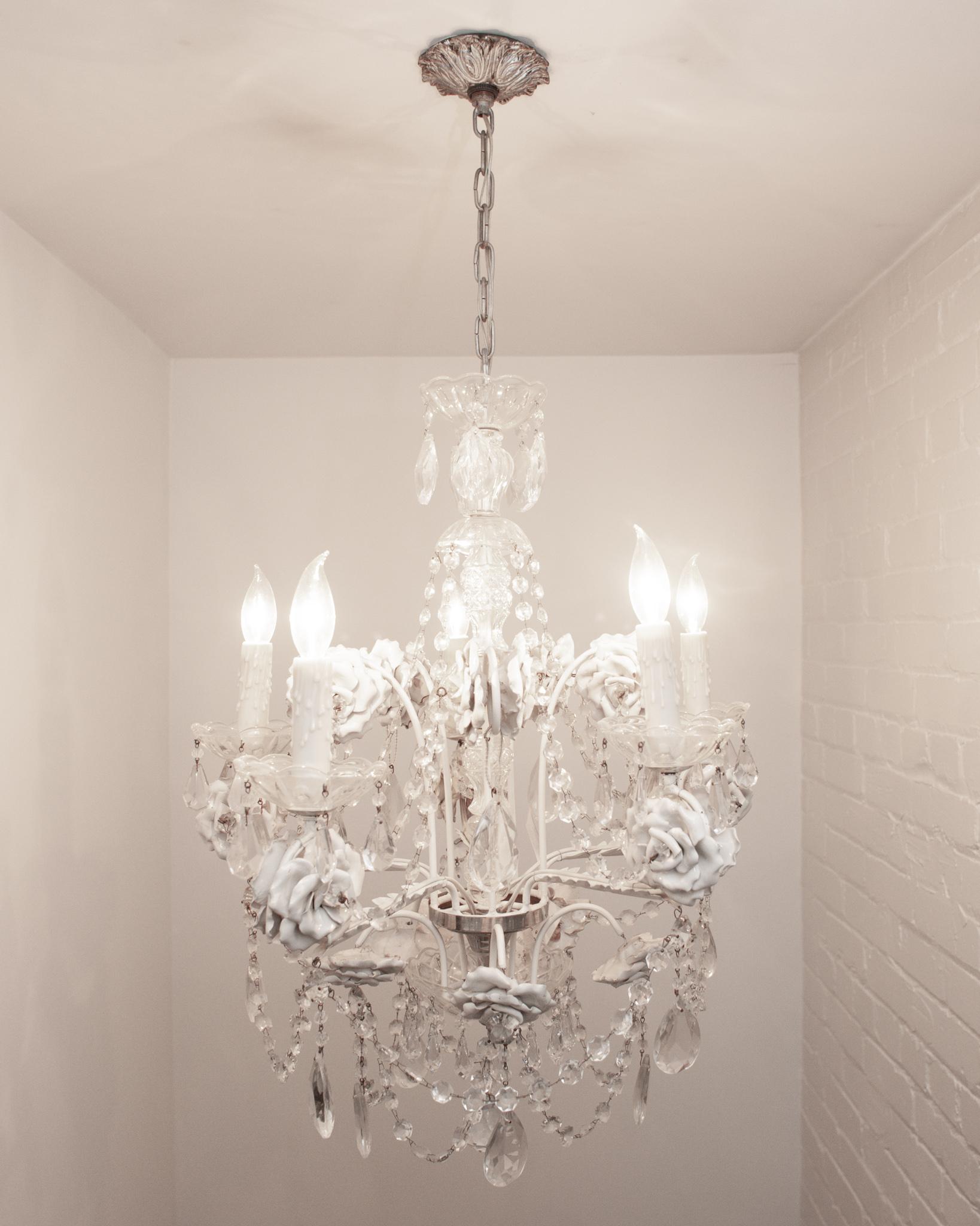 A beautiful large antique French chandelier, composed of white painted metal, crystal, and white glazed metal roses to resemble porcelain. Turn of the century production with original crystals.

Chandelier itself from bottom to top of crystal
