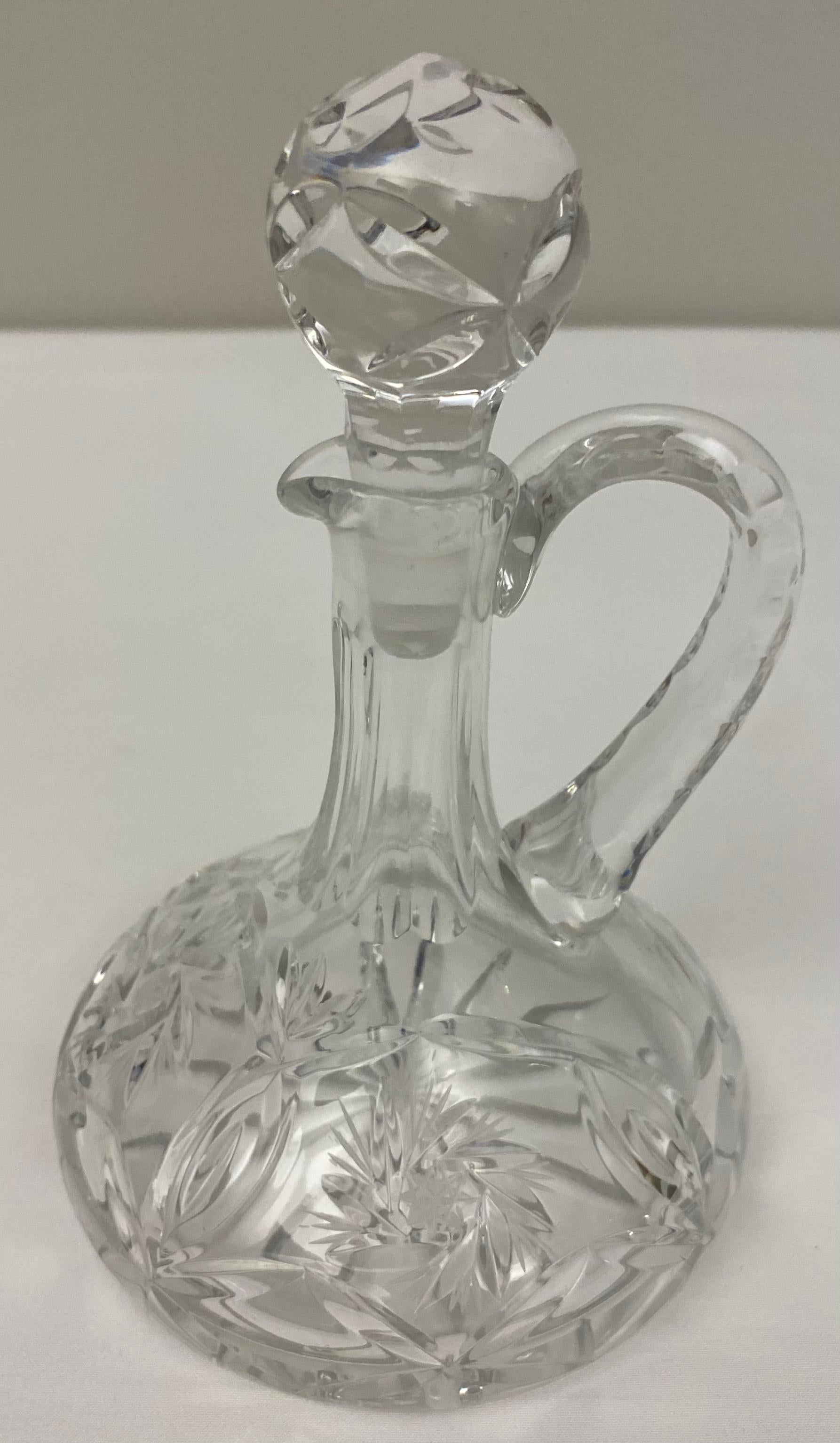Elegant Early 20th century French Art Deco style crystal oil and vinegar cruets or serving bottles in cut crystal with an etched design. A curved rim around the upper edges of the bottles allows for easier pouring. 

These serving pieces are sure to