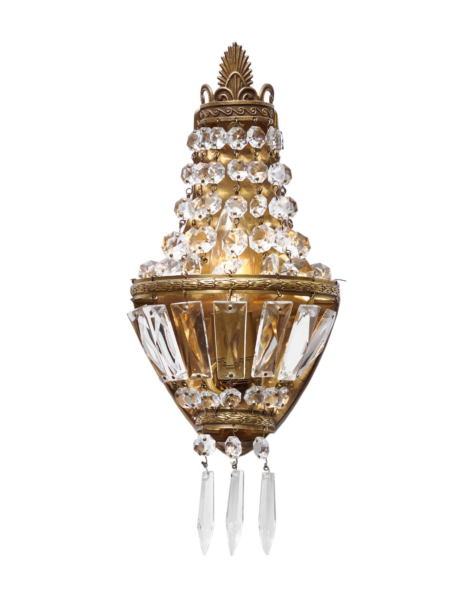 A pair of petite sconces from France in the Louis XVI style. Each fixture features an array of cut crystal cabochons and pendants on a finely cast gilt brass structure. They have been newly wired to fit US standards and are in very nice antique