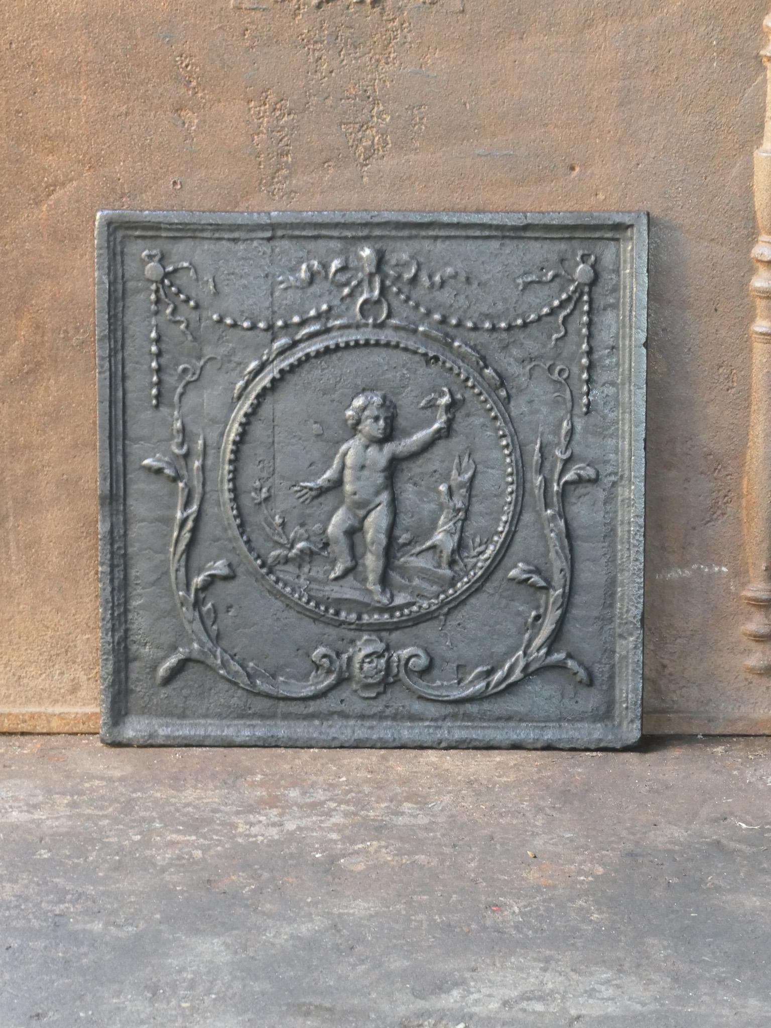 Late 18th or early 19th century French neoclassical period fireback with a cupid.

The fireback is made of cast iron and has a black / pewter patina. It is in a good condition and does not have cracks.