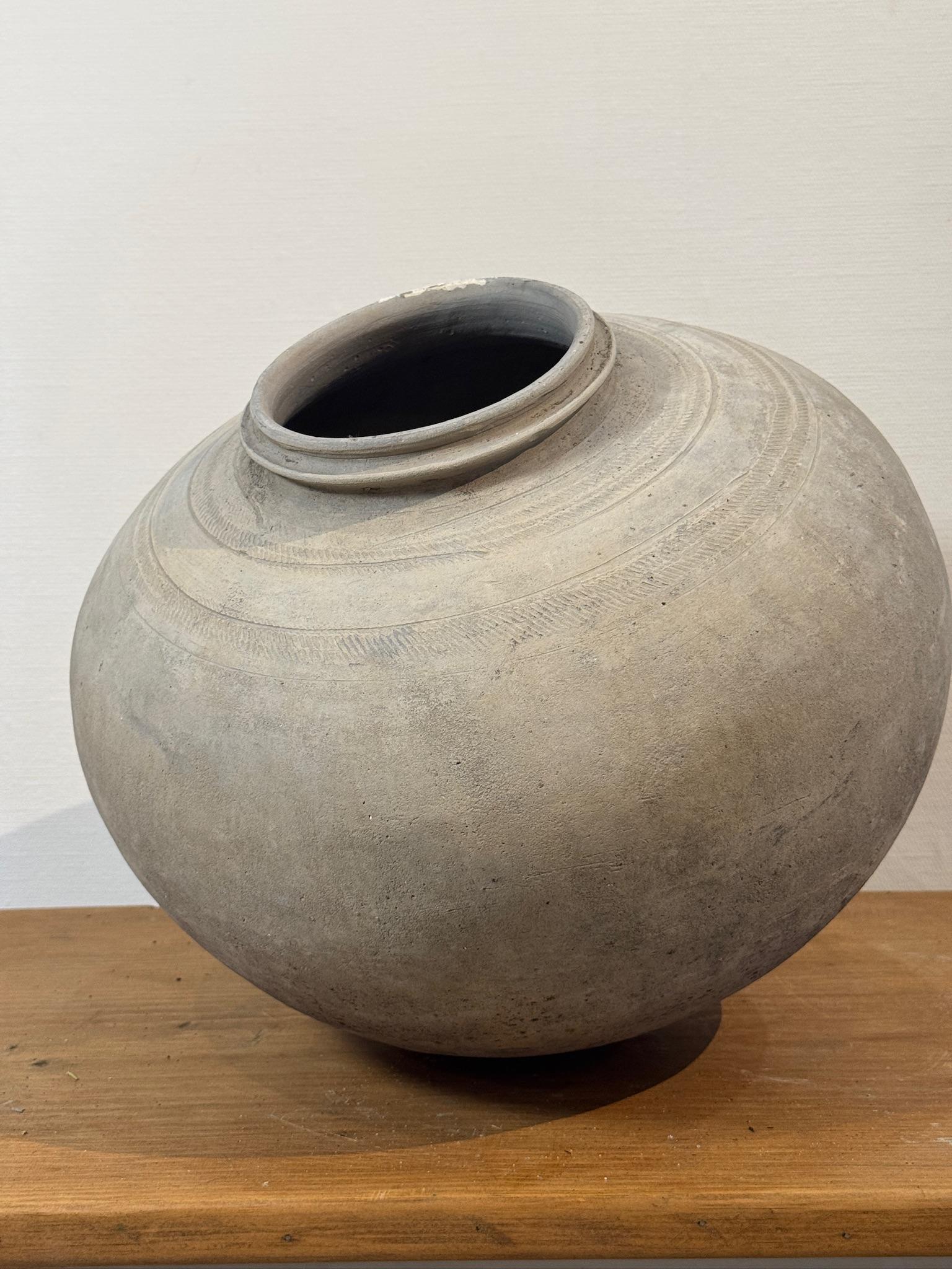 Esta exquisita urna antigua de terracota europea es un testimonio de artesanía atemporal, con una hermosa pátina desgastada e intrincados detalles grabados. Su clásica forma redondeada, el cuello ligeramente ahusado y el borde sutilmente acampanado
