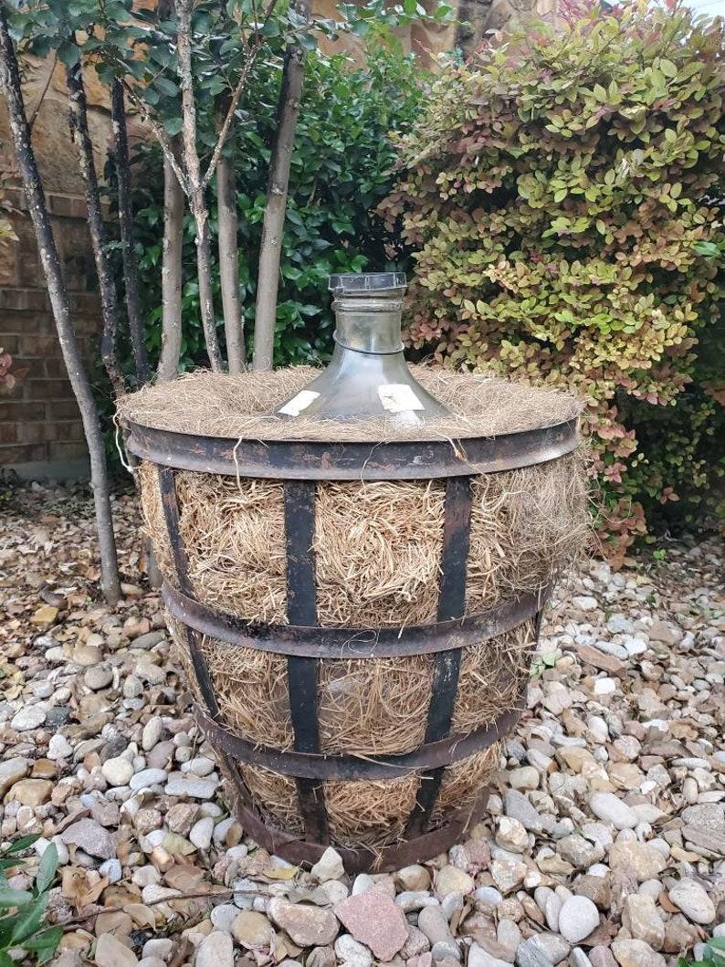 A beautiful French vineyard glass demijohn (also known as a carboy, lady Jane or jimmyjohn) bottle (vessel, vase, jug) in a period, patinated Vintner (winemaker) iron basket, fitted with straw. Handcrafted in France in the late 19th to early 20th