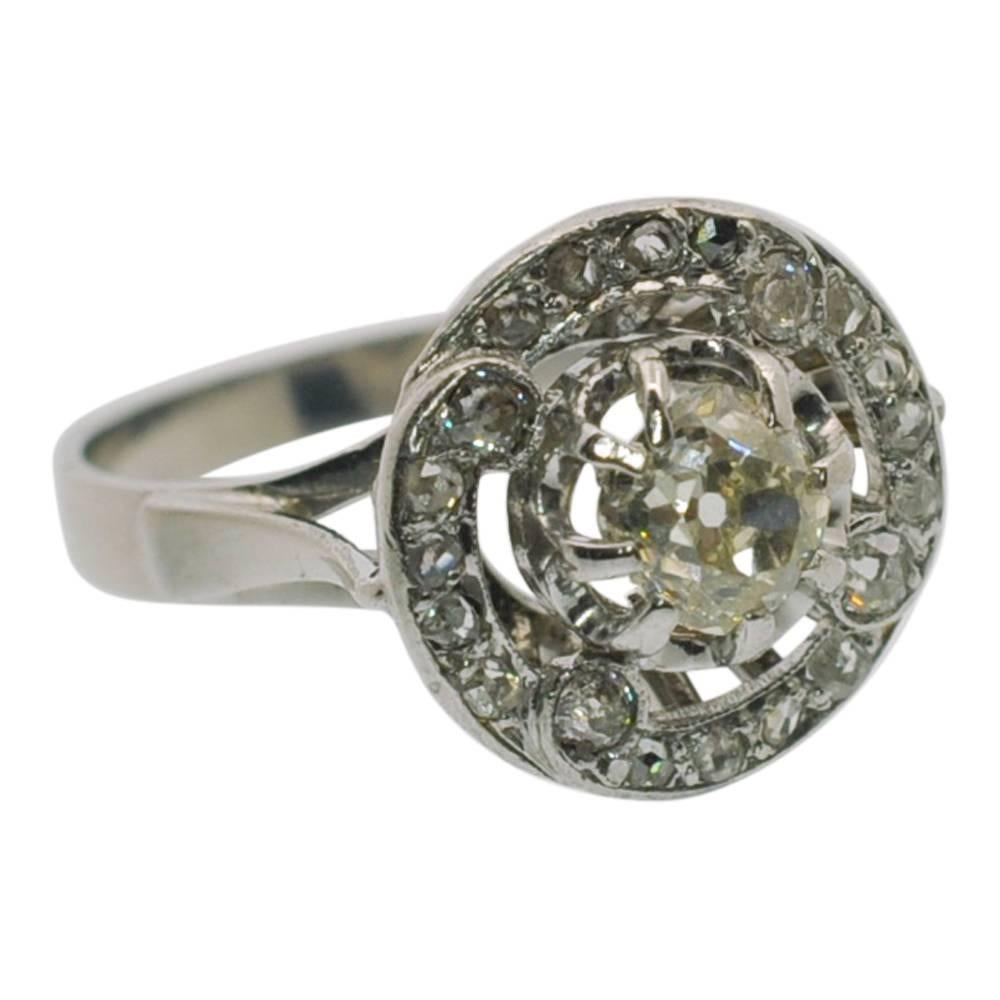 Antique French 1920s diamond halo style vintage engagement ring set in 18ct white gold;  the central Old European Cut diamond weighs 0.50ct, is claw set and mounted over a slight lip; it is surrounded by Rose Cut diamonds, 4 of which are slightly