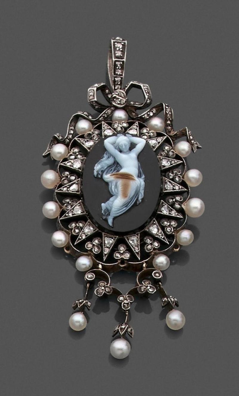 
Pendant in gold and silver of oval form decorated in the center of a cameo onyx forming opening medallion representing a woman in the antique in a surrounding of diamonds cut in pink and small pearls.
Height: 7.5cm Gross weight: 18.6g 