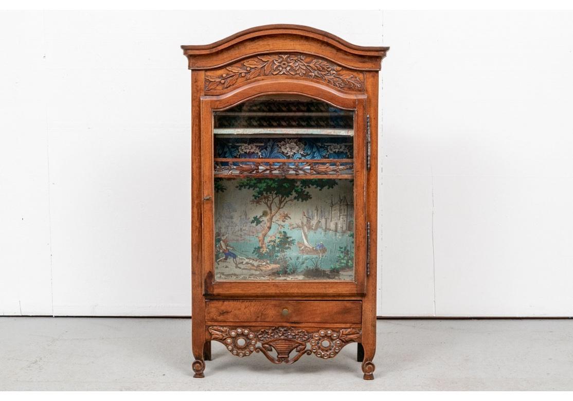 A rare hand-carved original condition Antique French Miniature Display Cabinet. With antique hand-written French labels on verso. A lovely diminutive carved fruitwood display cabinet with curved bonnet over a carved frieze with vines. A lower drawer