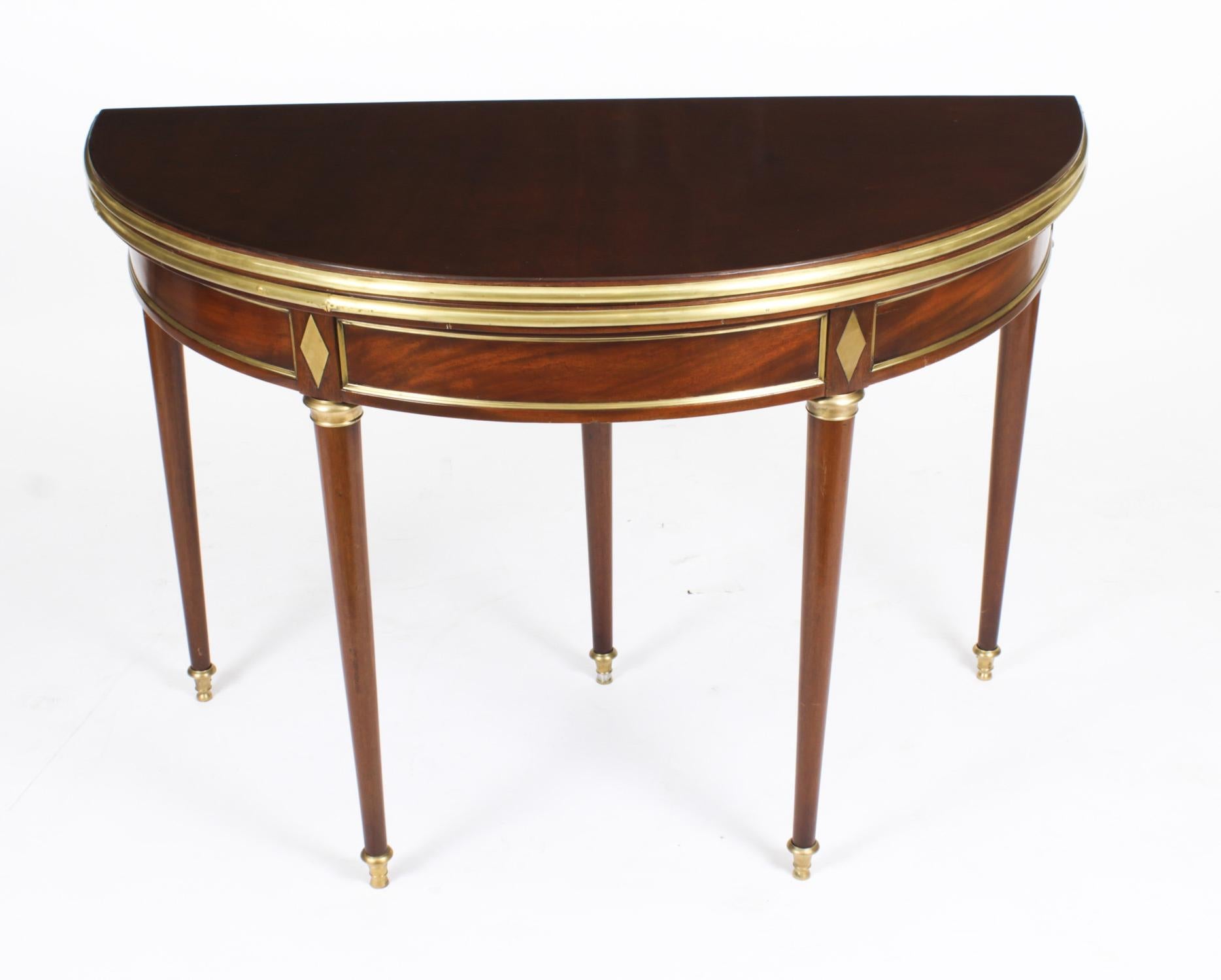 This is a very attractive antique French Directoire flame mahogany and brass mounted demi-lune ganes table, circa 1820 in date.
 
THE BOTANICAL NAME FOR THE MAHOGANY THAT THIS CARD TABLE IS MADE OF IS SWIETENIA MACROPHYLLA AND THIS TYPE OF MAHOGANY