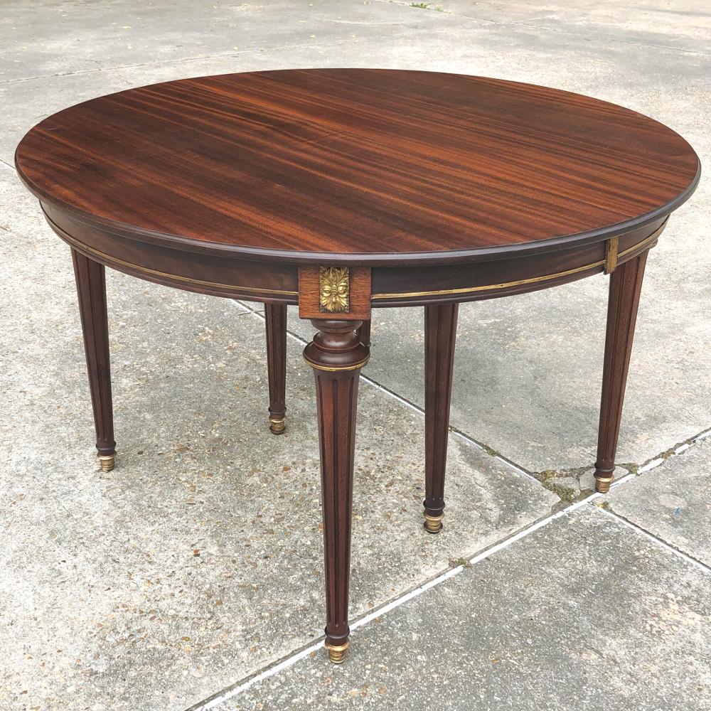 aAntique French Directoire dining table includes 2 leaves, and was handcrafted from Fine imported mahogany to create an elegant dining atmosphere, indeed! Subtle cast brass accents include bordering, rosettes, bands around the tapered & fluted legs,