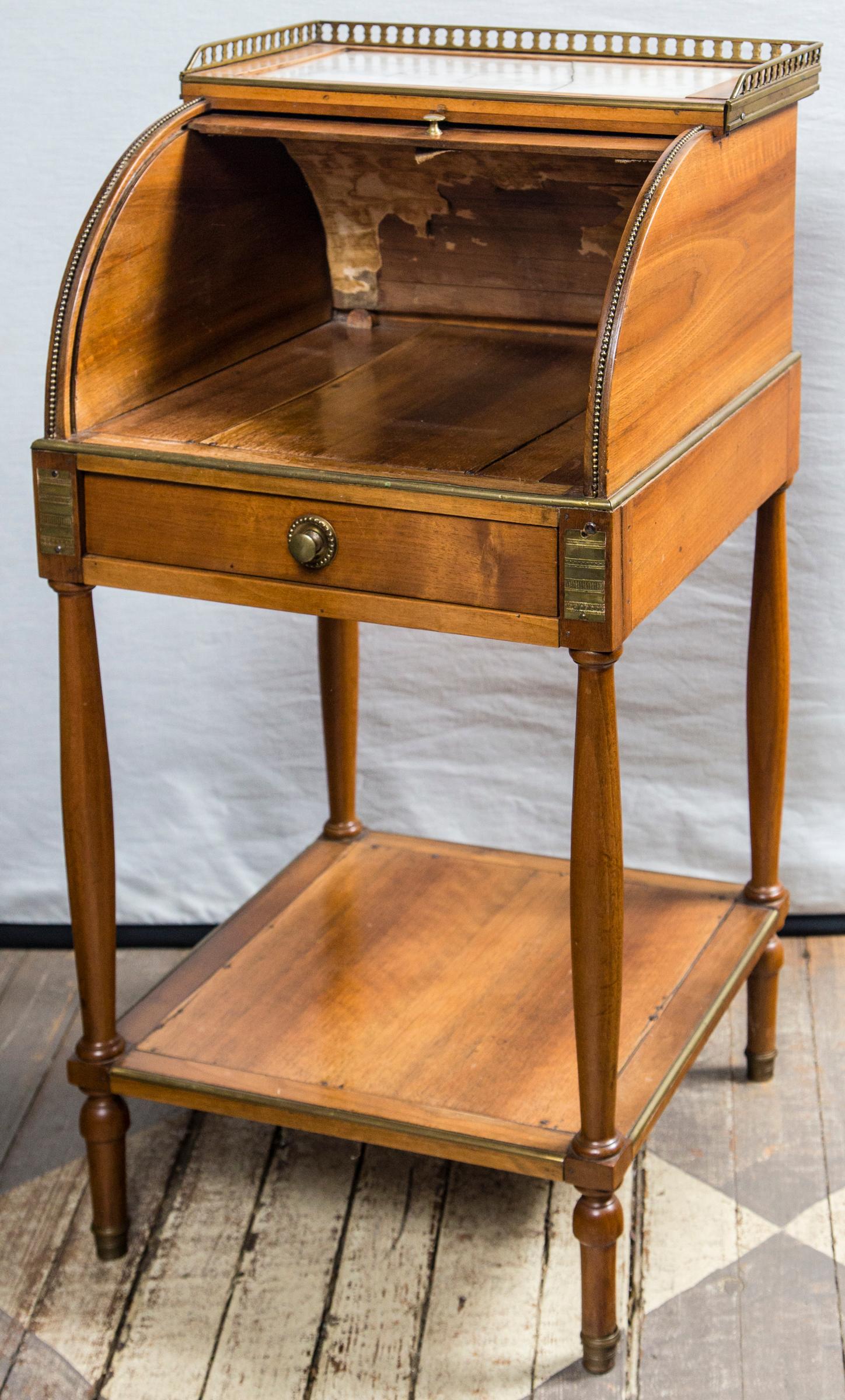 Made of fruit wood with a marble top (cracked). Brass gallery surrounds the marble top. Brass pulls and mounts. The inside of the top shows old canvas and paper.