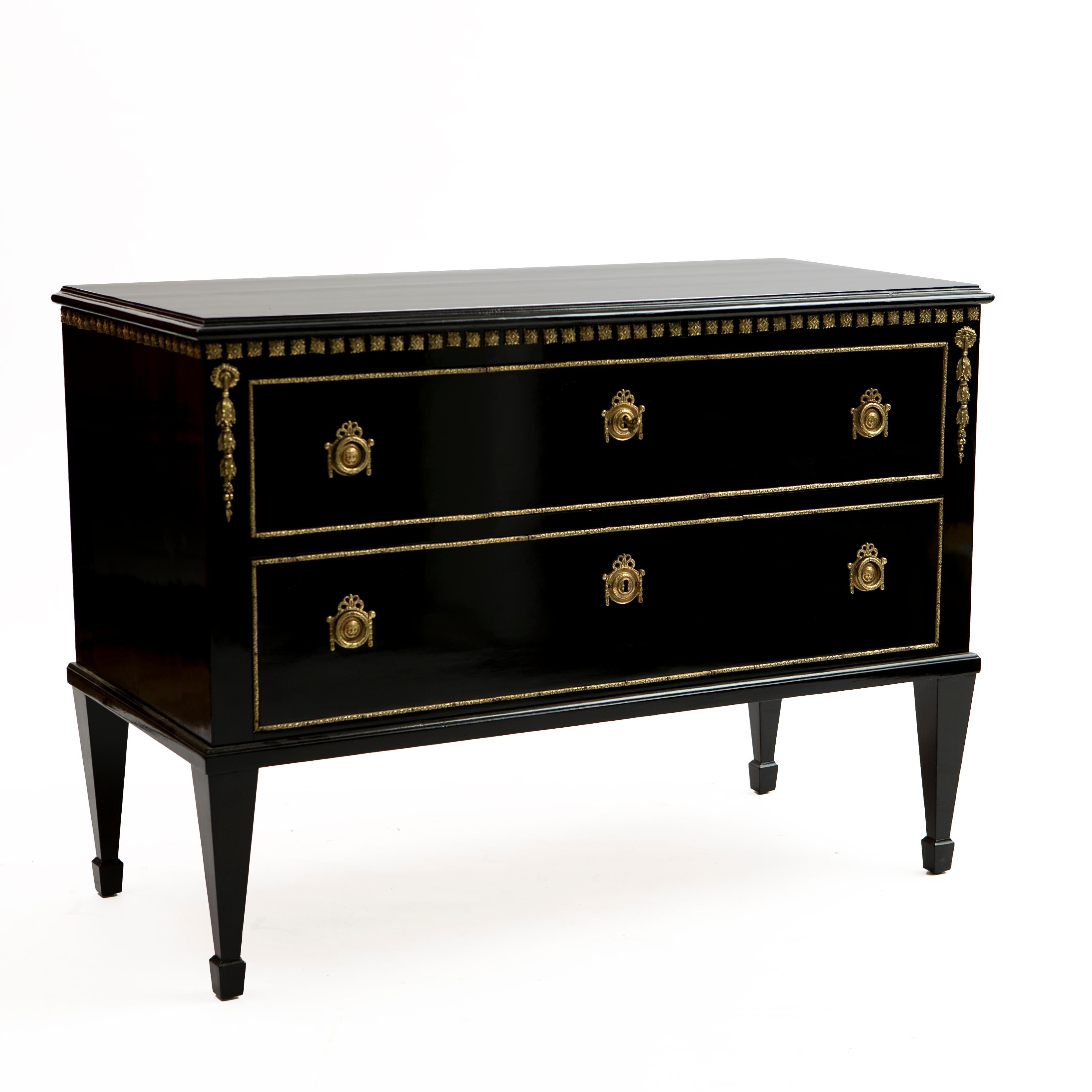 Decorative French commode with two drawers in the Directoire manner.

Black polished mahogany with bronze detailing and fitted with bronze ring pulls and key guards. Raised by square tapered legs.

France approx. 1900.