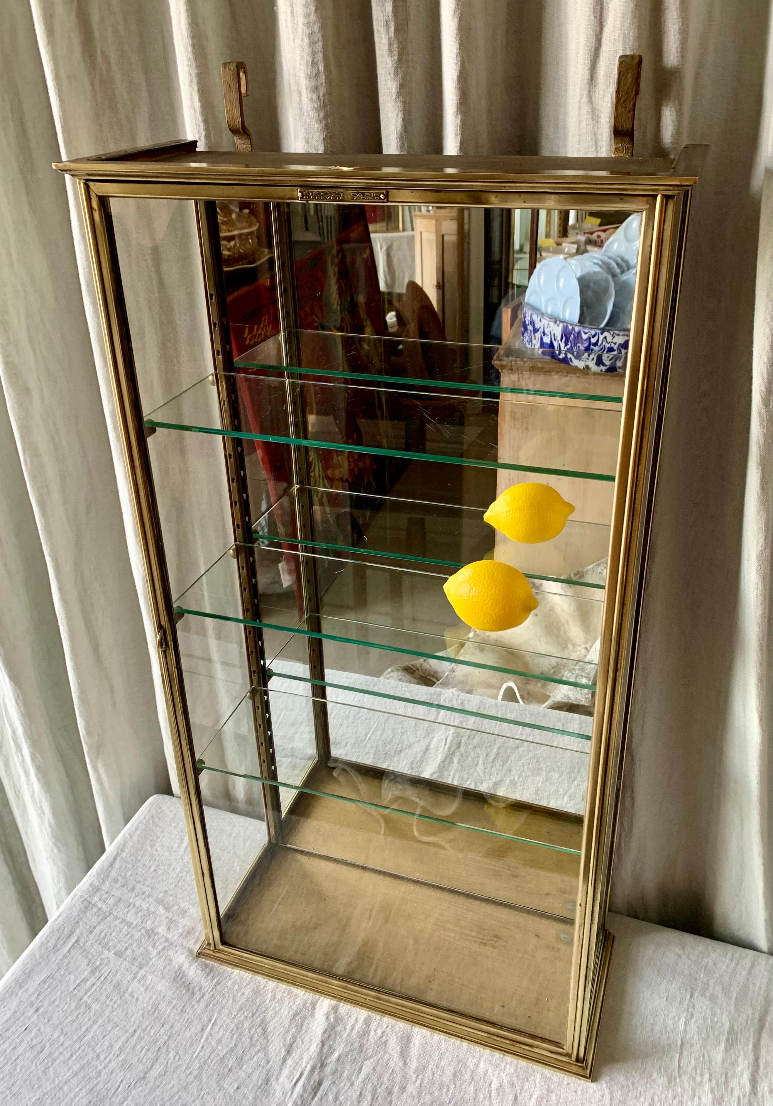 Antique French brass display cabinet or vitrine for hanging on the wall. The cabinet has perfect patina according to its age and used to serve as a display for tobacco, perfume etc. in a shop. A nice cabinet for the kitchen, bathroom or dressing