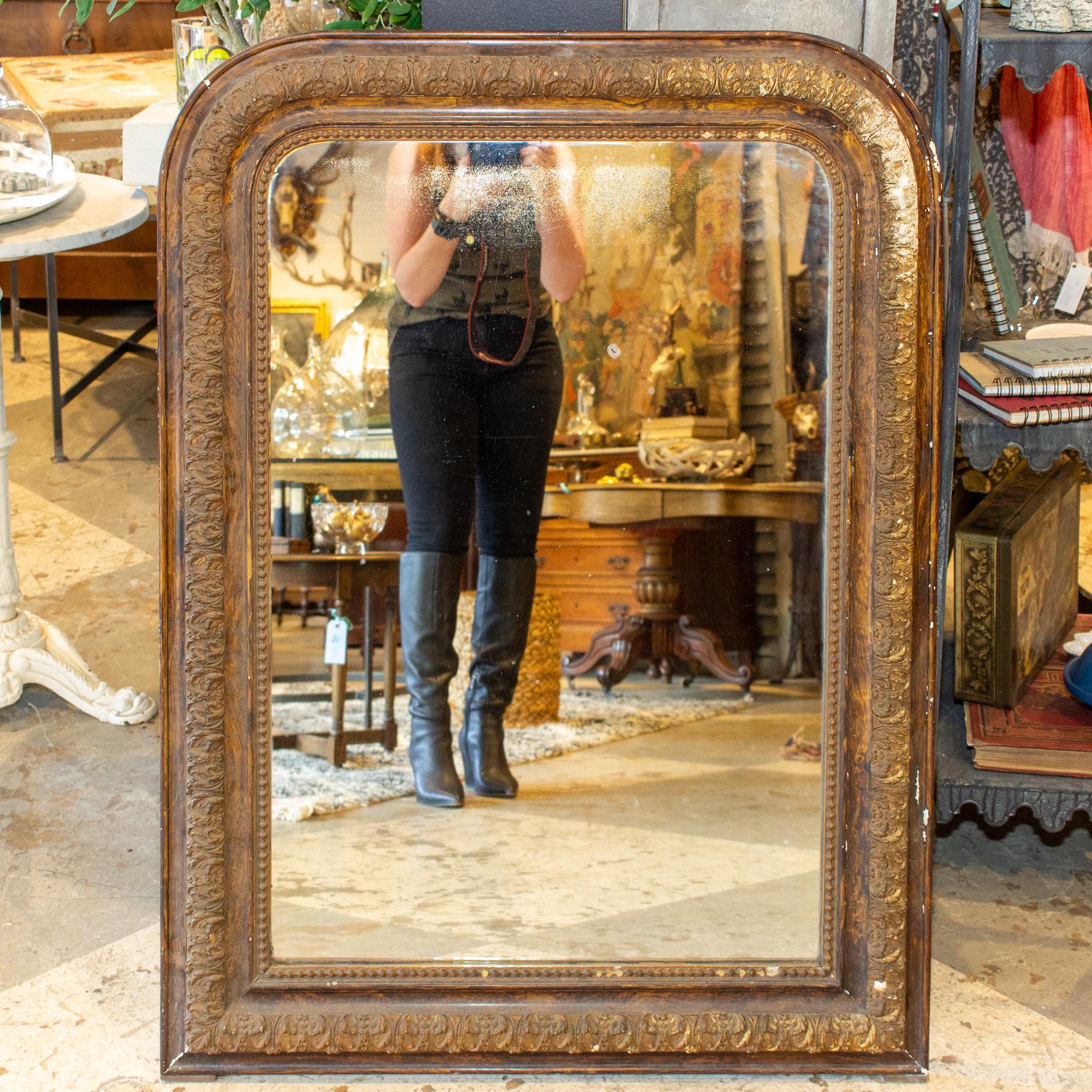 This antique French Louis Philippe mirror has a distressed finish with a raised floral leaf pattern molding along the center of the frame and a beaded interior edge. Mirror is in good condition, with some spotting from age present. The painted