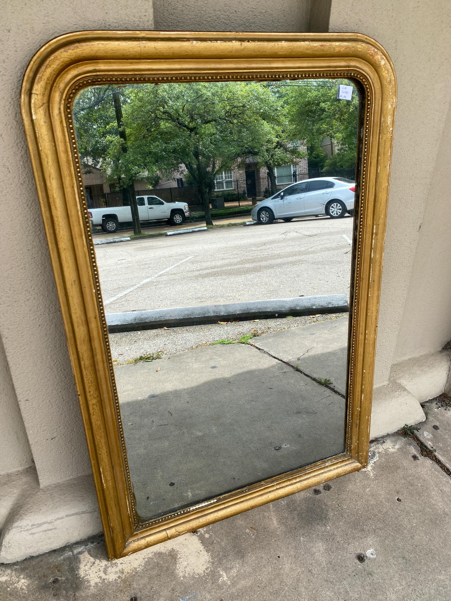 This antique French Louis Philippe mirror has a distressed gilt finish, which looks to have been painted over the original finish some time ago. The beaded edge has some losses, but this mirror has that classic sparkle to the glass, revealing just