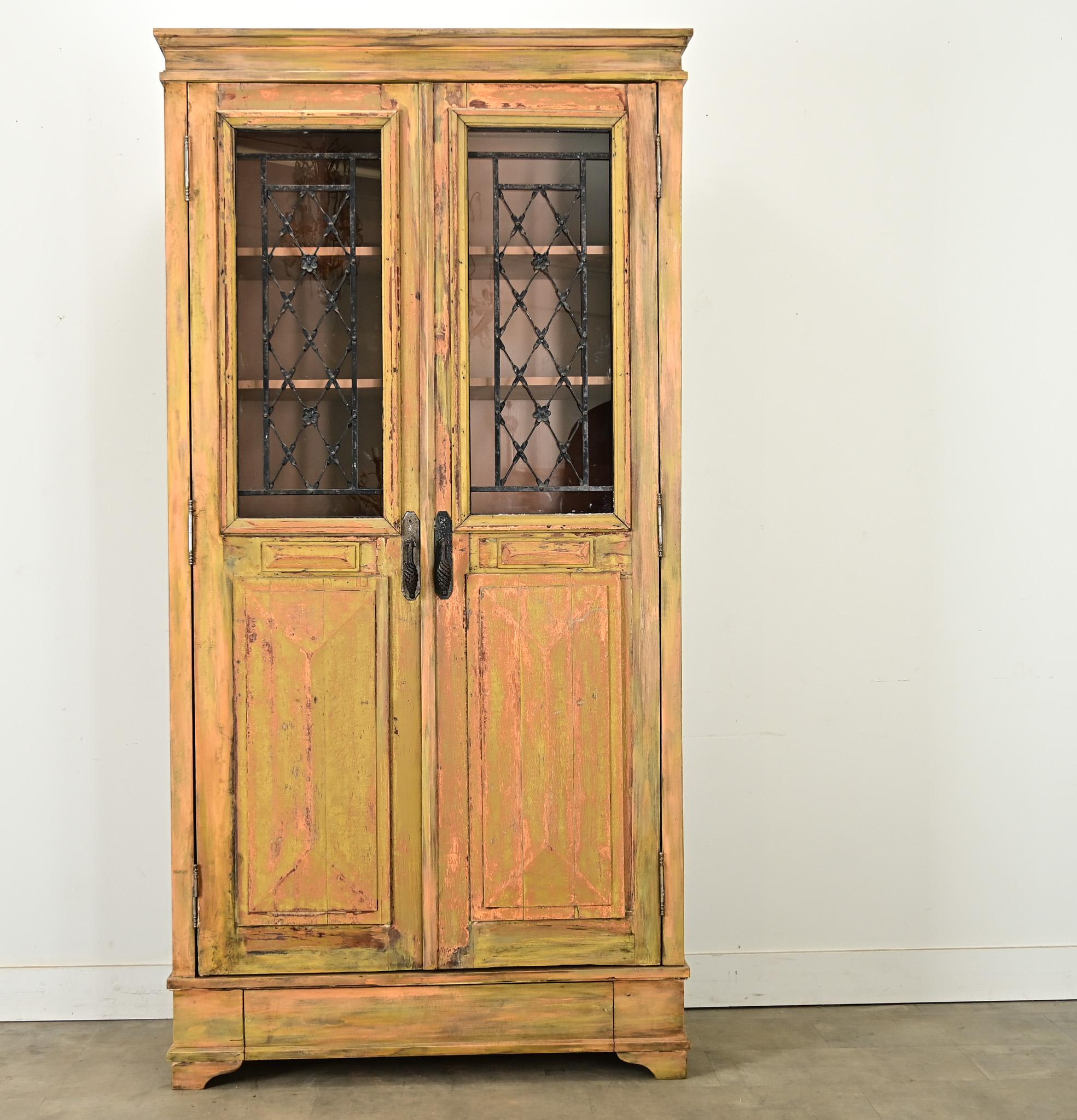 New, custom armoire or bibliotheque made by repurposing an antique French door from circa 1800, cut to essentially create two closet doors. What was a former exterior door shows remarkable layers of paint, blending gold, green, and salmon pink