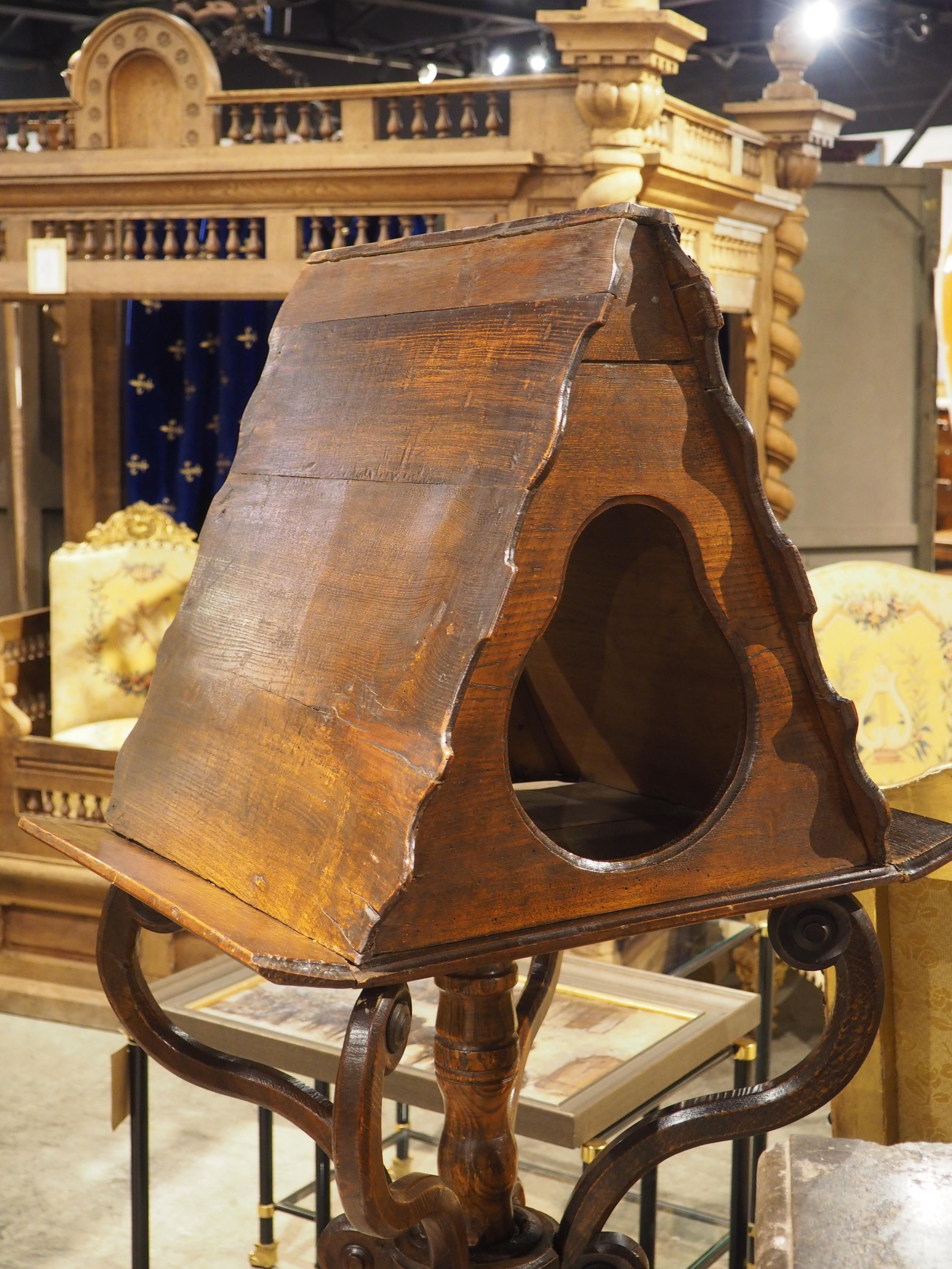 Sculpté à la main en trois parties (la plate-forme à double face, la tige tournée et la base robuste à volutes), ce lutrin français date d'environ 1700. Combinant le noyer et le pin, le lutrin présente une riche patine brun foncé, avec quelques