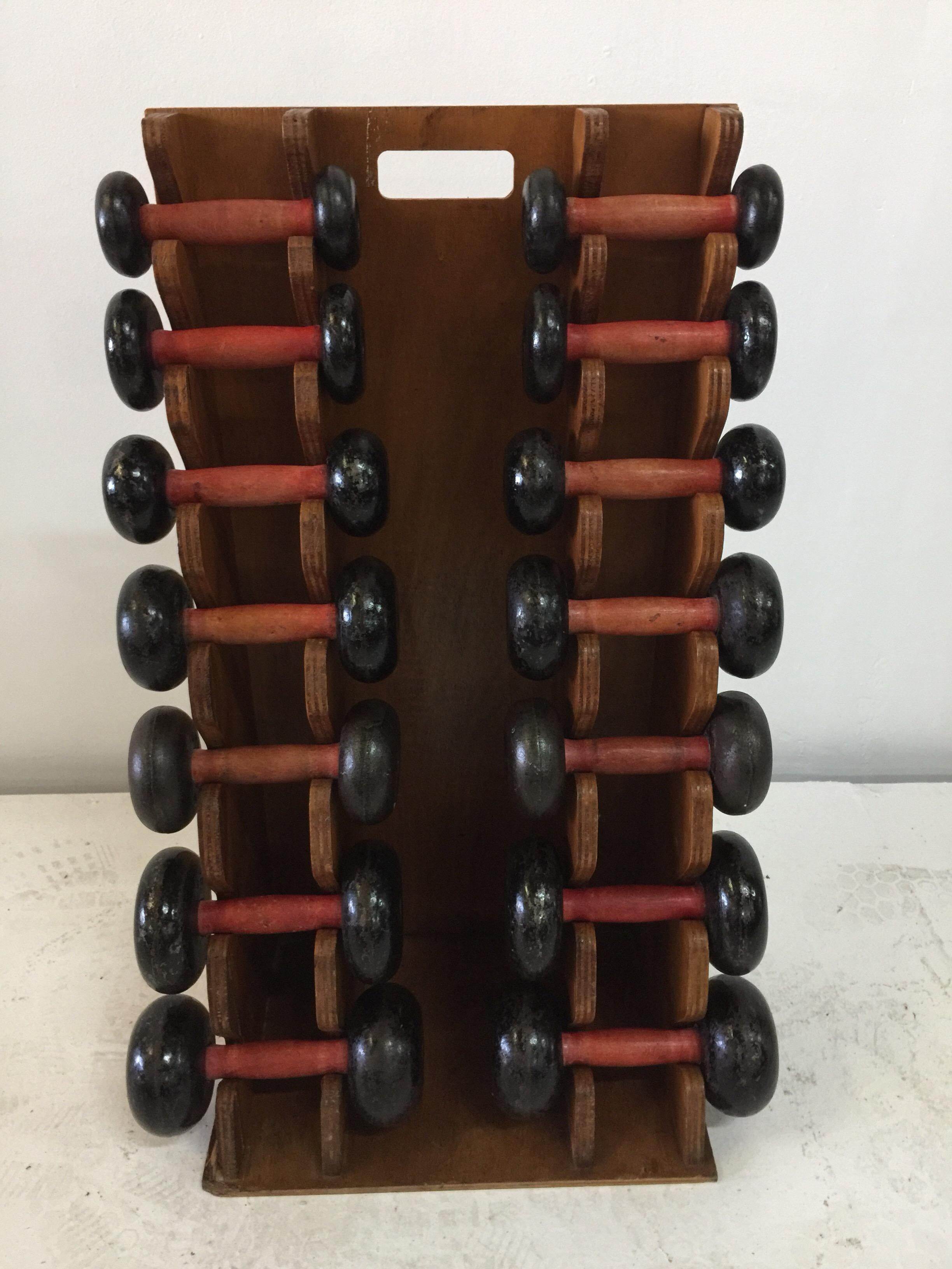This extraordinary weights set on stand consists of 7 pairs of dumbbells with painted wooden handles and cast iron weights. All original and shows great aging and patina. The set is solid and functional. Perfect addition to a home gym.  Weights