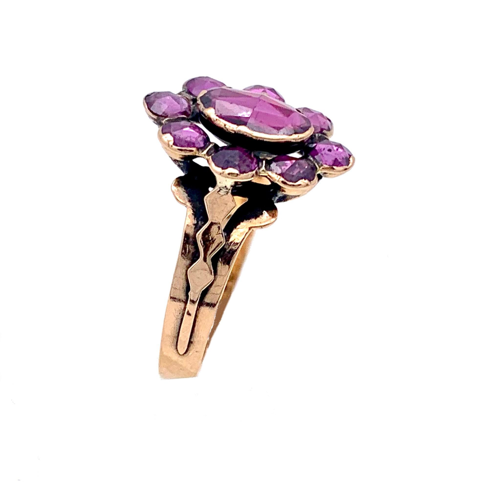 This beautiful earl nineteenth century ring was created in the south of France. It is made from 18 karat rose gold and carries a hallmark.
The ring is designed as a flower. A large oval facetted amethyst from Perpignan is surrounded by eight smaller