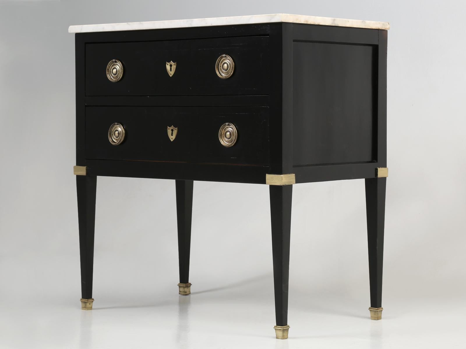 Antique French commode in an ebonized finish with its original marble top, which does have a chipped corner. Because of its petite size and marble top, this antique French commode would make the perfect nightstand table. 
**There are two holes that
