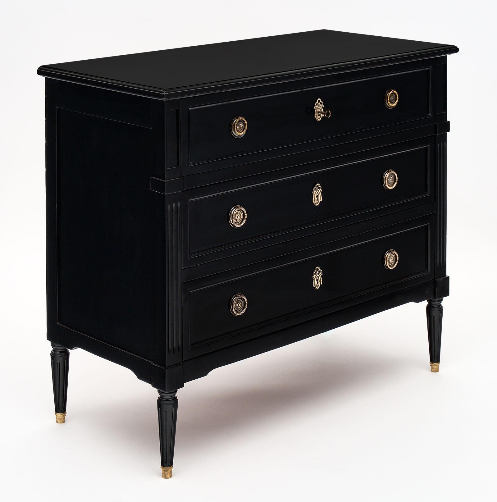 Ebonized antique French Louis XVI chest of drawers made of mahogany and finished with an ebony French polish for luster. This piece has three dovetailed drawers, tapered legs, and finely cast hardware original to the piece. The top drawer has a