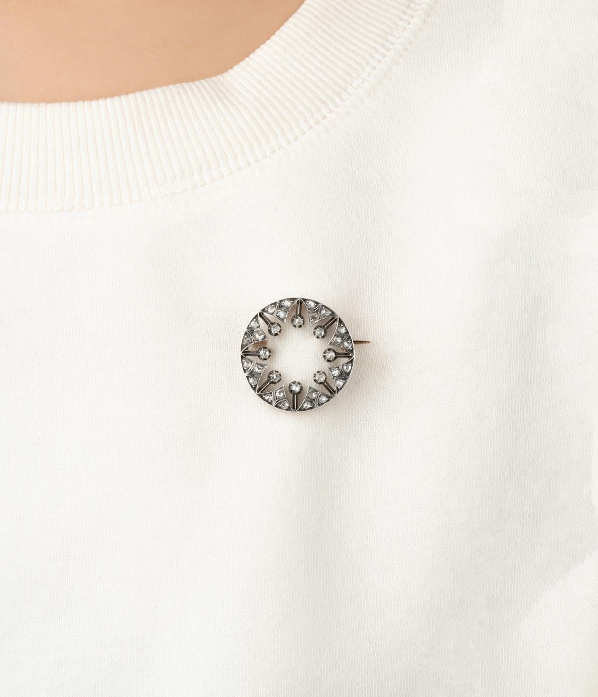Broche ancienne en or rose 18 carats (750 millièmes) et en argent 800 millièmes du début du 20ème siècle. De forme ronde, elle est sertie de 32 diamants de taille rose en serti grain.

Poids total du bijou : 6,6 g environ.
Diamètre 2,6 cm
Poinçon