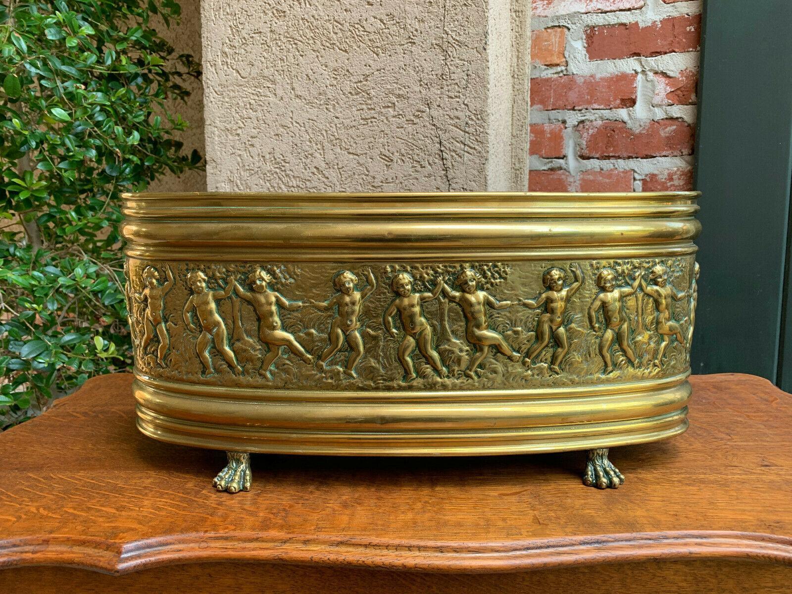 ~Direct from France~
~Lovely antique embossed brass French jardinière~
~Stunning, huge band of dancing cherubs amid trees, around the entire oval shape, set up on four brass ‘paw feet’~
~circa 1900~

Measurements
8.5” height x 18.5” x