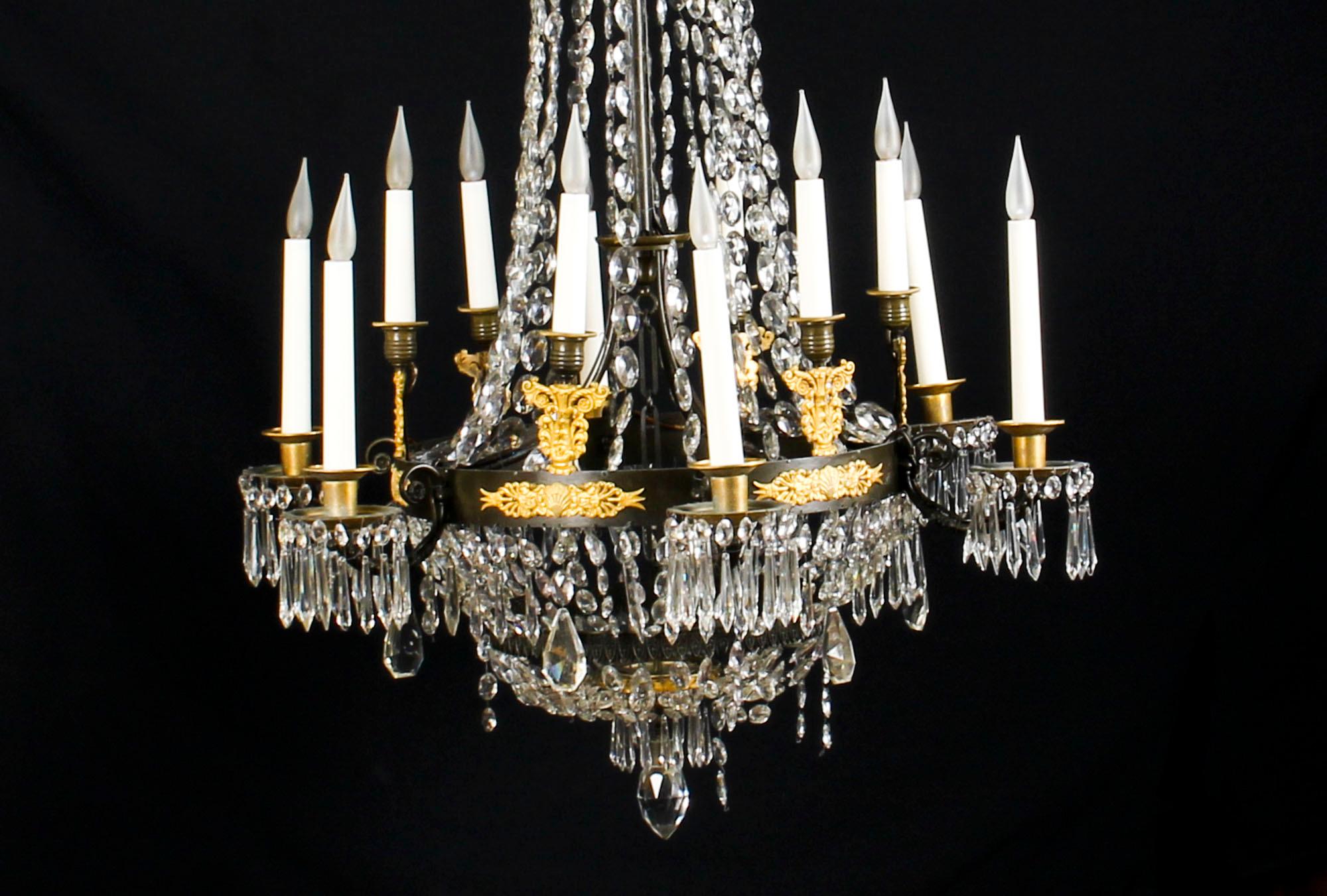 This is a wonderful French Empire patinated ormolu and crystal chandelier with twelve lights circa 1850 in date.

The chandelier is of inverted trumpet form with a foliate cast corona hung with faceted pendants and bead swags overall descending to a