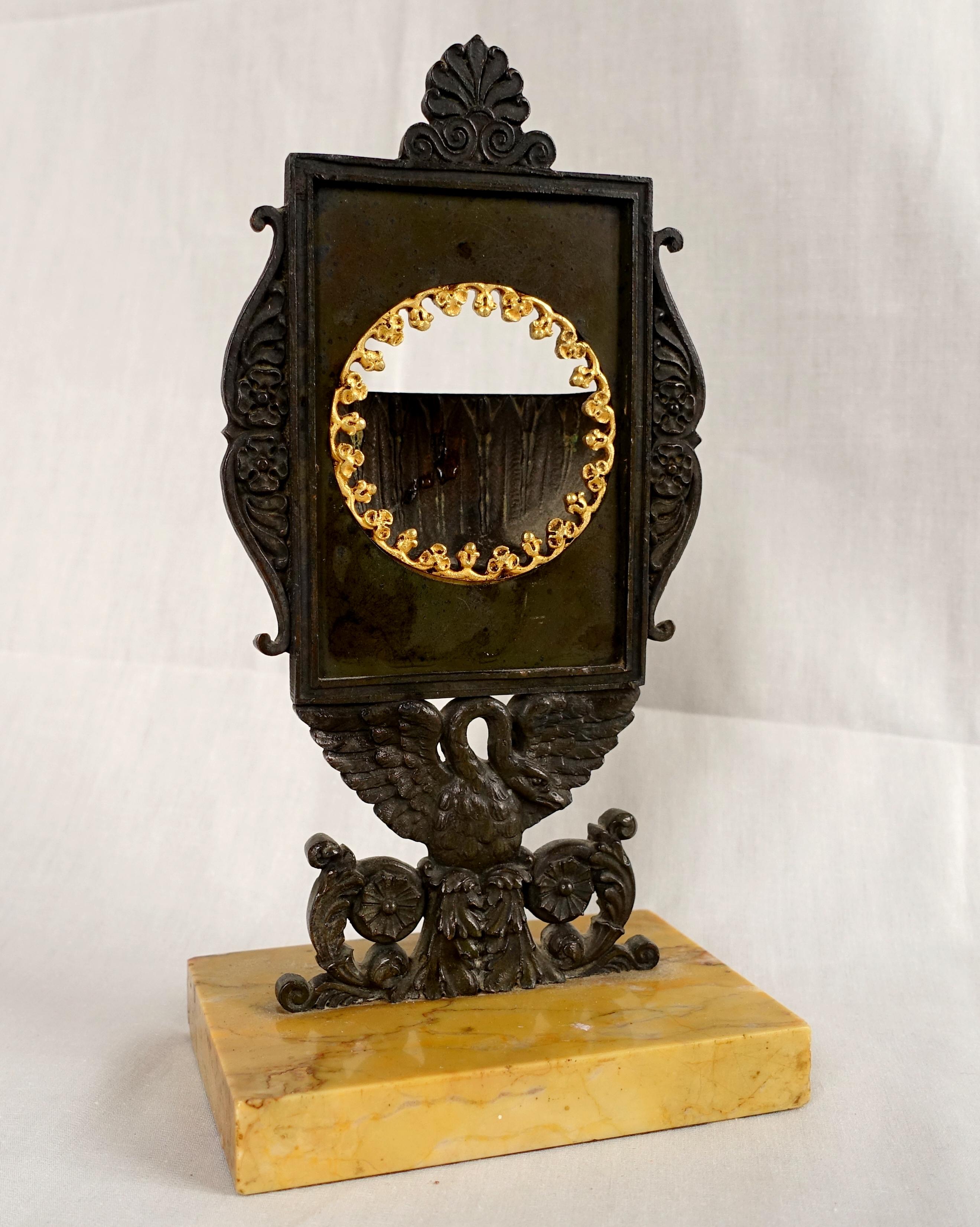 Ancien porte-montre Empire français, début du 19ème siècle vers 1820.
Le porte-montre permet de convertir une montre de poche ouverte en horloge de bureau ou de table.
Beau et rare modèle représentant un bouclier en bronze patiné tenu par un cygne