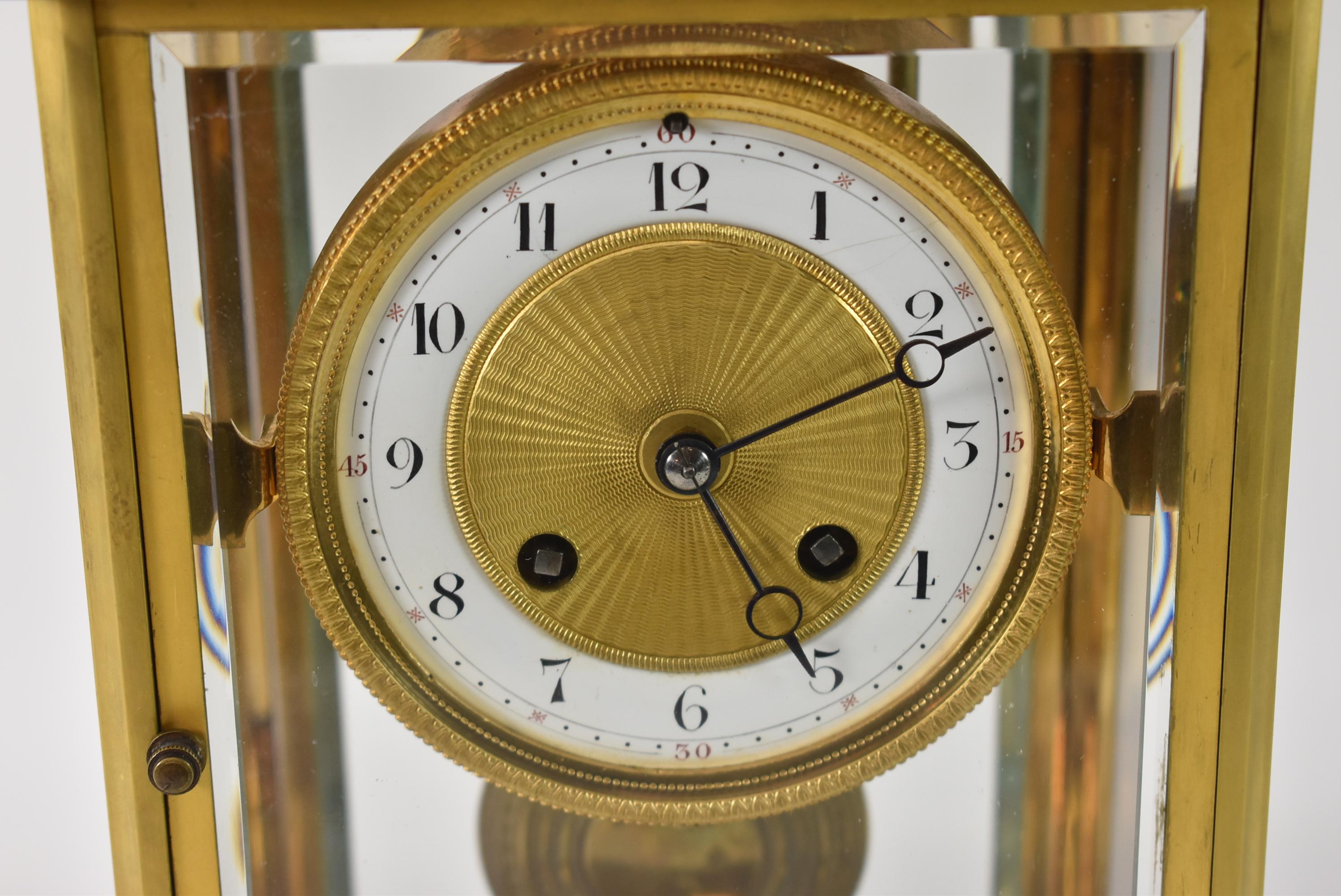 A beautiful brass clock with gold dore finish. Beveled glass panels with a porcelain dial and time and strike. French works. Running condition. Corner crack in one glass panel.