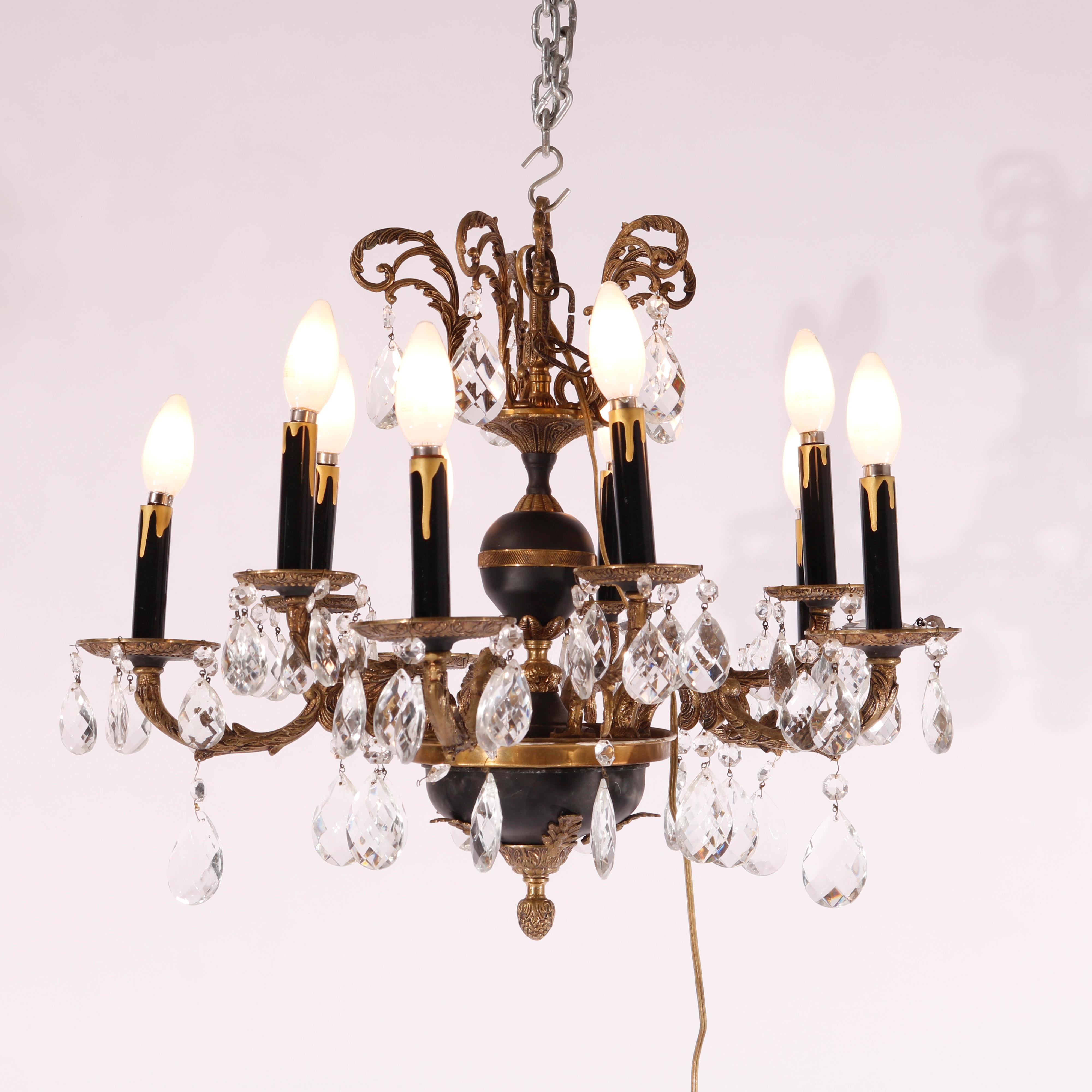 An antique French Empire chandelier offers ebonized and gilt metal frame with scroll and foliate elements, hanging cut crystal highlights throughout, c1930

Measures - 19