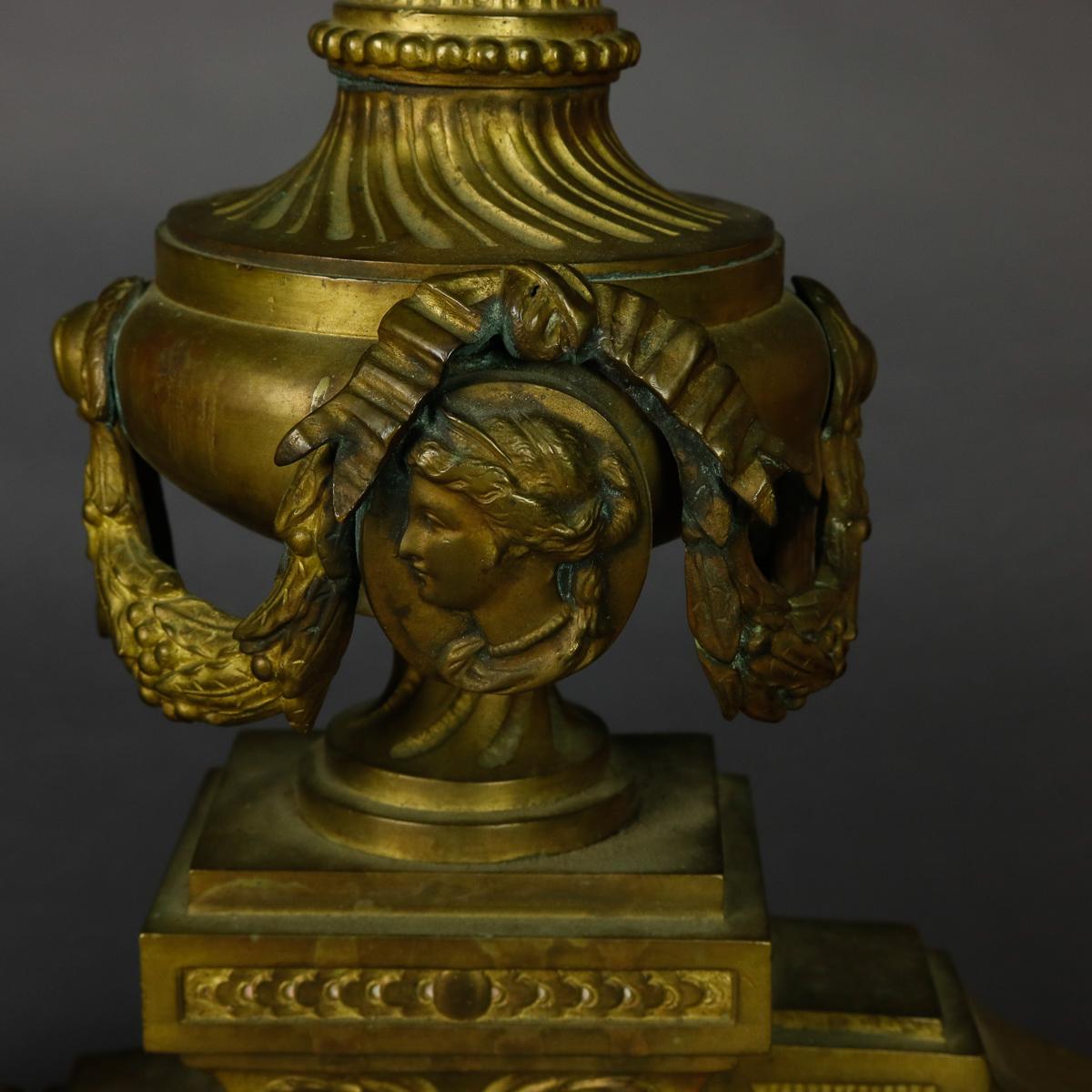 A set of antique French Empire andirons offer cast bronze in urn form with drape, flame, and central female mask elements, without firedogs, circa 1840

Measures: 15