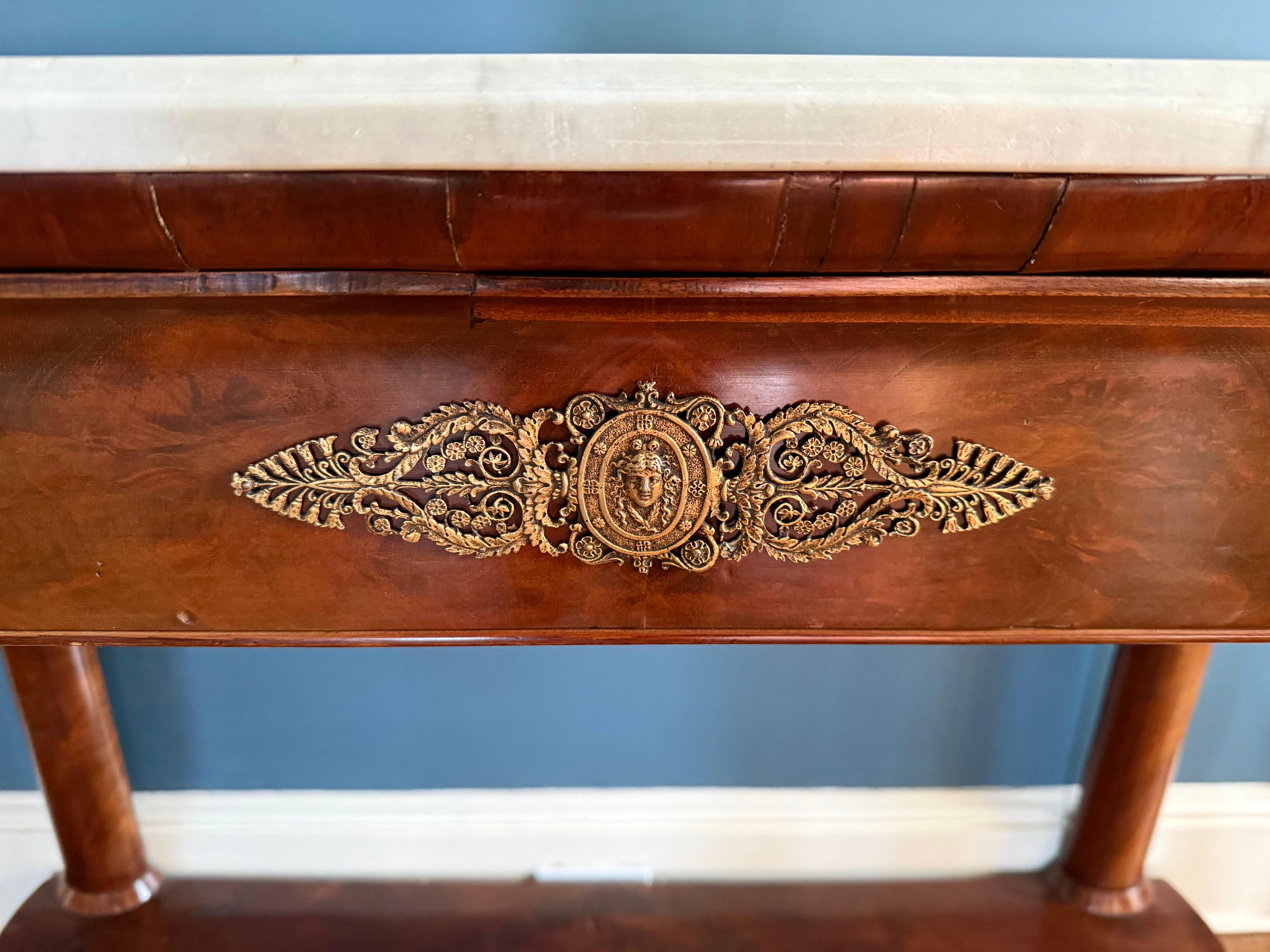 Antique French empire Louis XVI mahogany two-tiered console server with removable marble top.  Features one felt lined drawer and gilt accents supported on four legs with front legs terminating to carved paw feet.