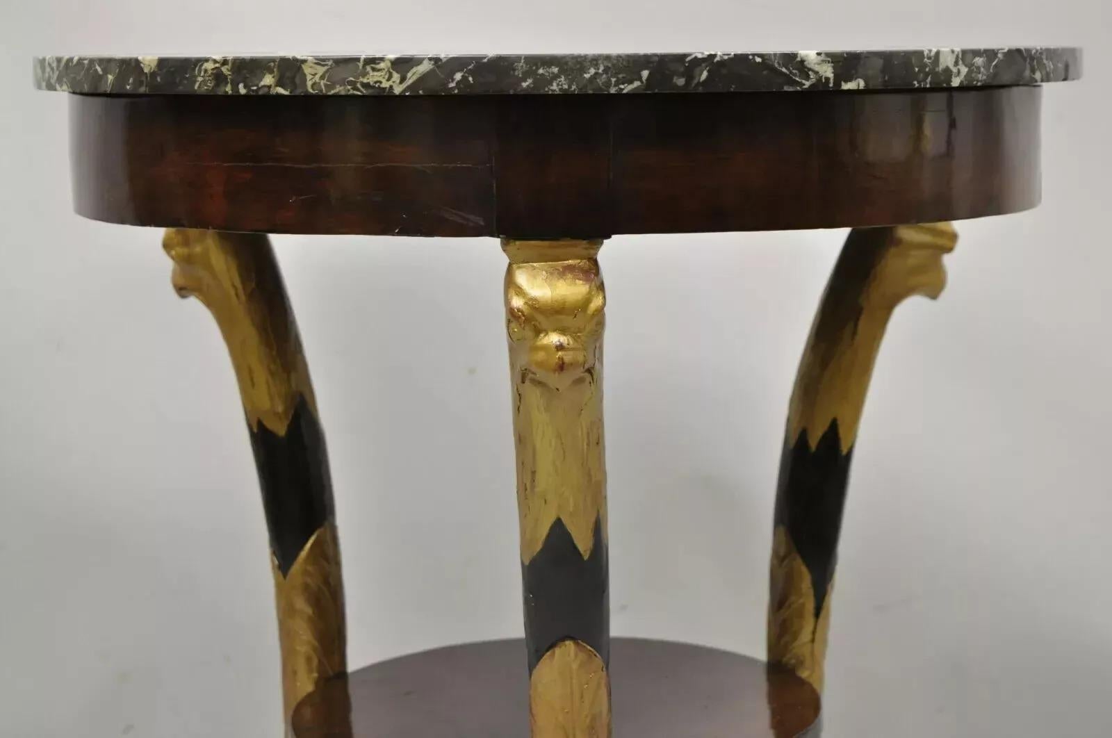 Ancienne table centrale ronde Empire néoclassique à plateau de marbre sculpté à l'aigle. Cet objet présente un plateau rond en marbre à bord surélevé, des têtes d'aigle dorées, une étagère inférieure, une finition ébonisée, des pieds en patte d'oie,