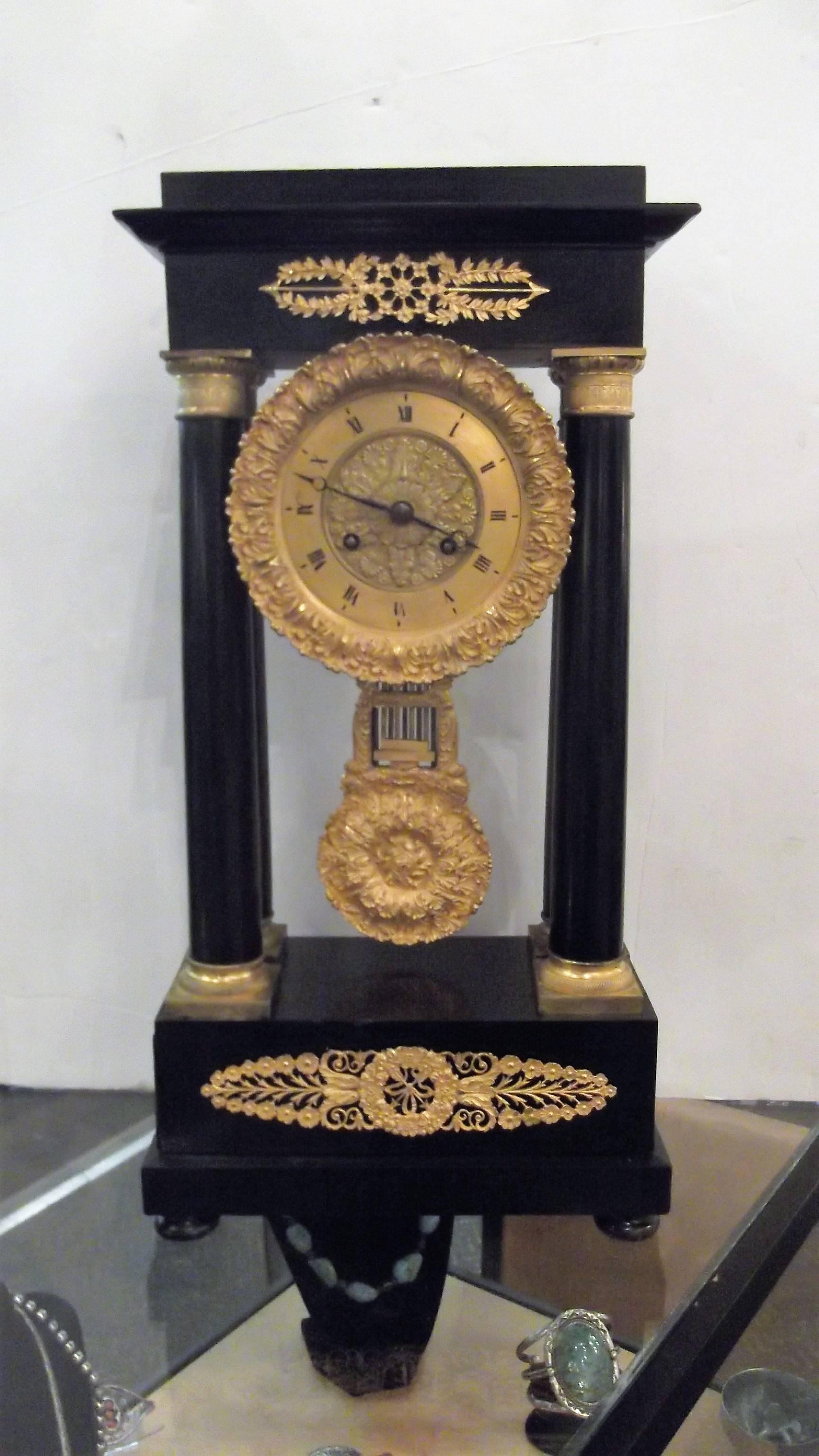 A classic French First Empire Block protico Clock, circa 1820 with beautifully cast original gilt bronze mounts on ebonized walnut. 
The four columns hold up the newly cleaned and serviced works with a magnificent original pendulum, the face of the