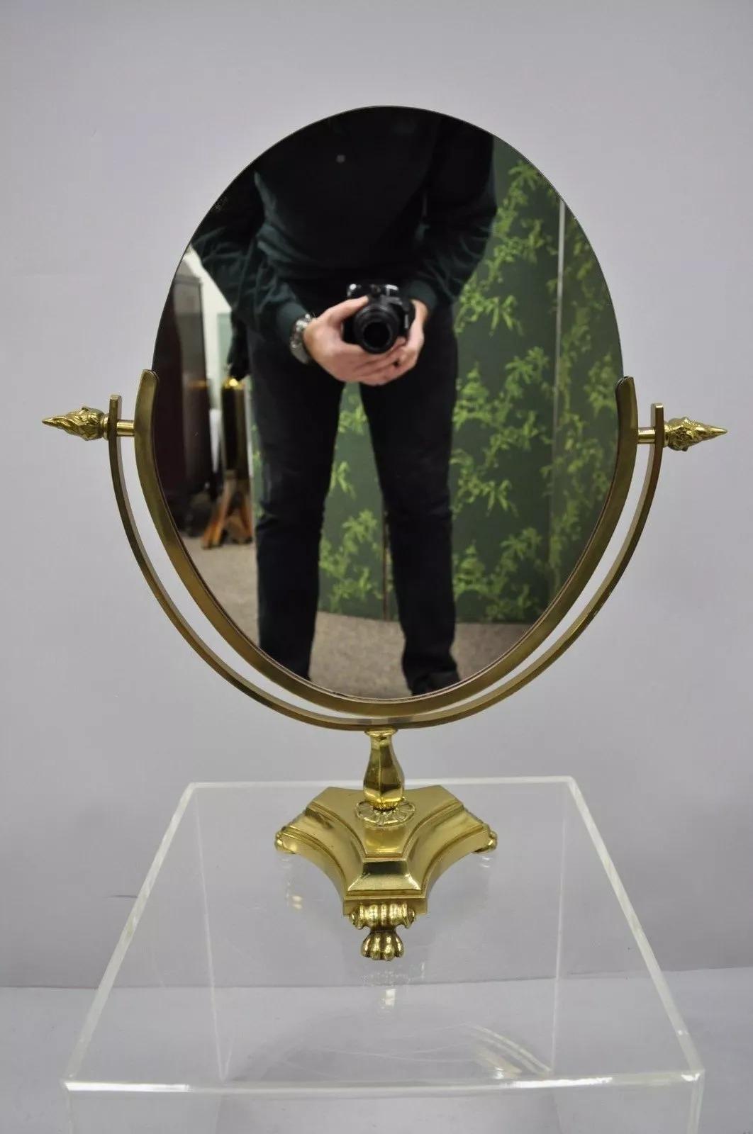 Antique French Empire Style Brass Paw Foot Oval Vanity Double Mirror. Item features 3 brass paw feet, mirror on BOTH sides, flame finials, great style and form. Circa Early 20th Century. Measurements: 23.5