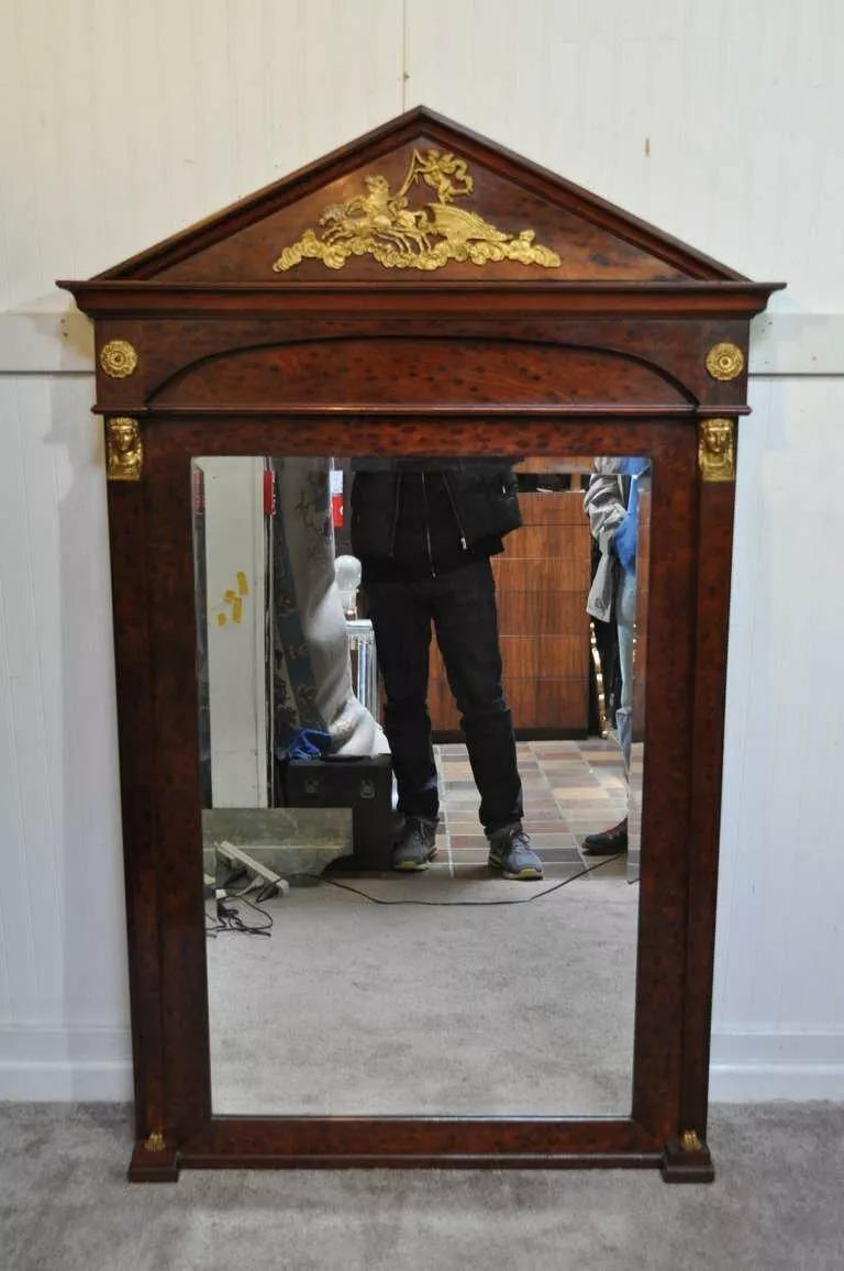 Miroir de style Empire en bronze, bronze doré, bois de ronce, grand miroir Trumeau. L'objet se compose de bois de ronce, de verre biseauté, de magnifiques montures en bronze comprenant des pieds humains figurés, des visages de jeunes filles et un