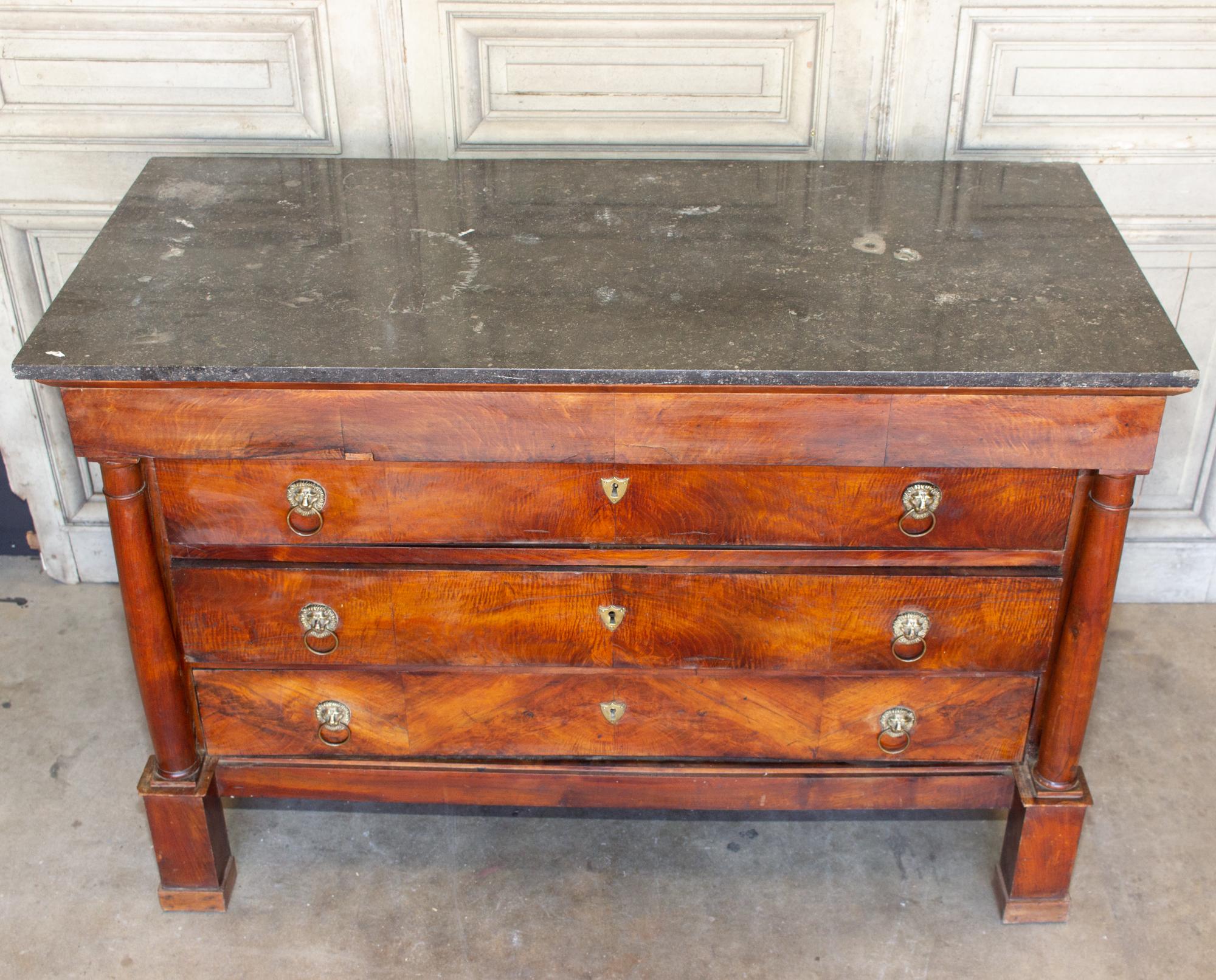 This antique French empire style chest features wonderful lion's head pulls and a fossilized marble top. The four-drawer design includes one narrow top drawer and three larger lower drawers. No key is included, but this piece does have shield-shaped
