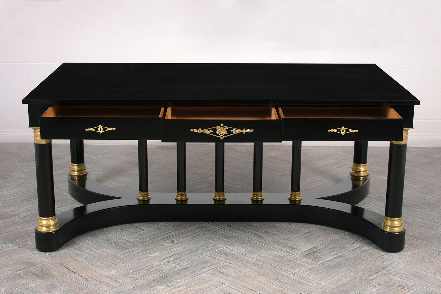 This 1900s French Empire-style partner desk is made of mahogany wood with an ebonized and lacquered finish. On each side of the desk there are three drawers with decorative brass keyhole plates. The pedestal base features a thick X-shaped Silhouette