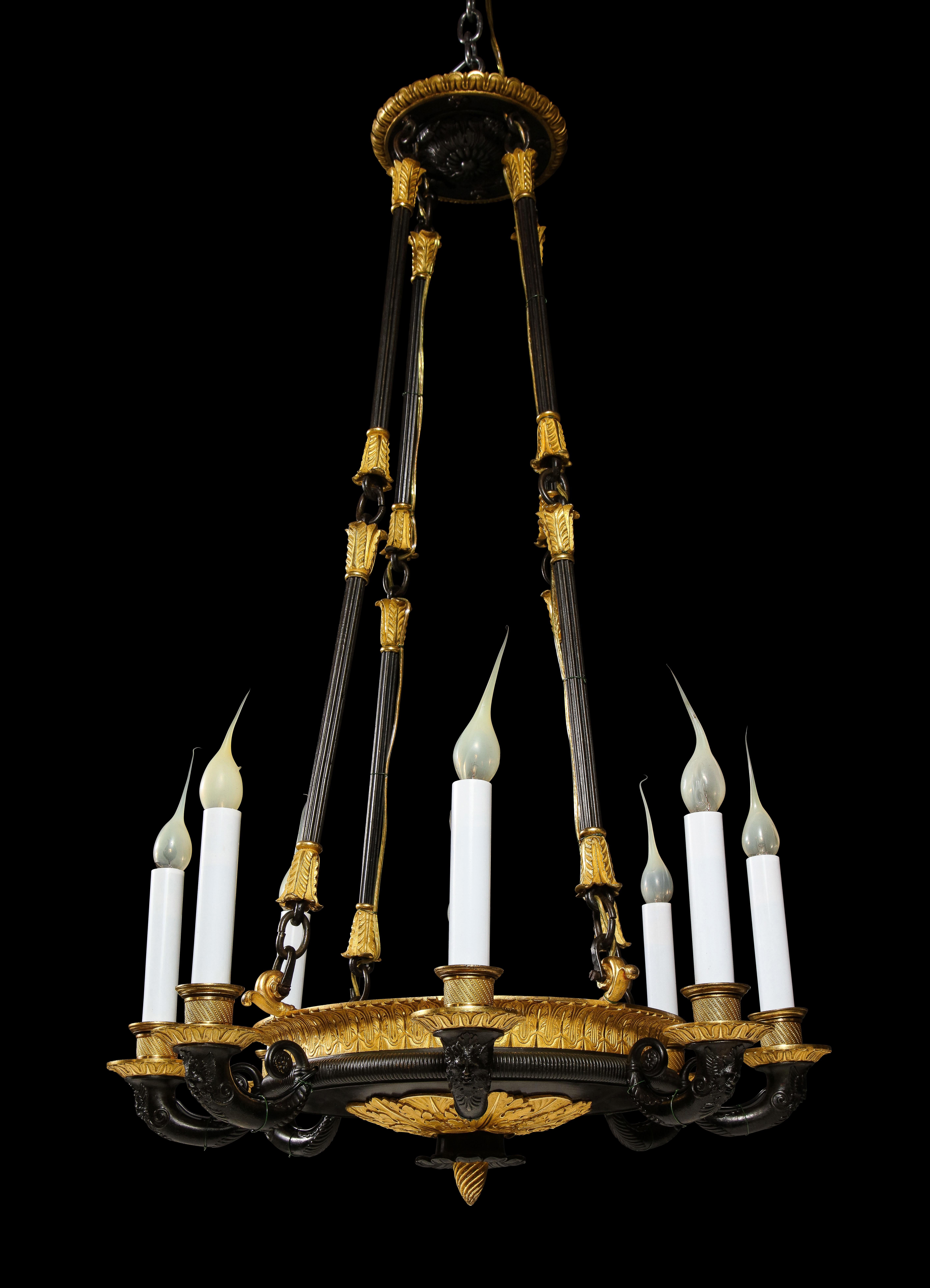 A Superb Antique French Empire style gilt bronze and patinated bronze 8 light chandelier of fine quality. This unique neoclassical chandelier is embellished with figural masks and neoclassical motifs further adorned with a top original canopy.