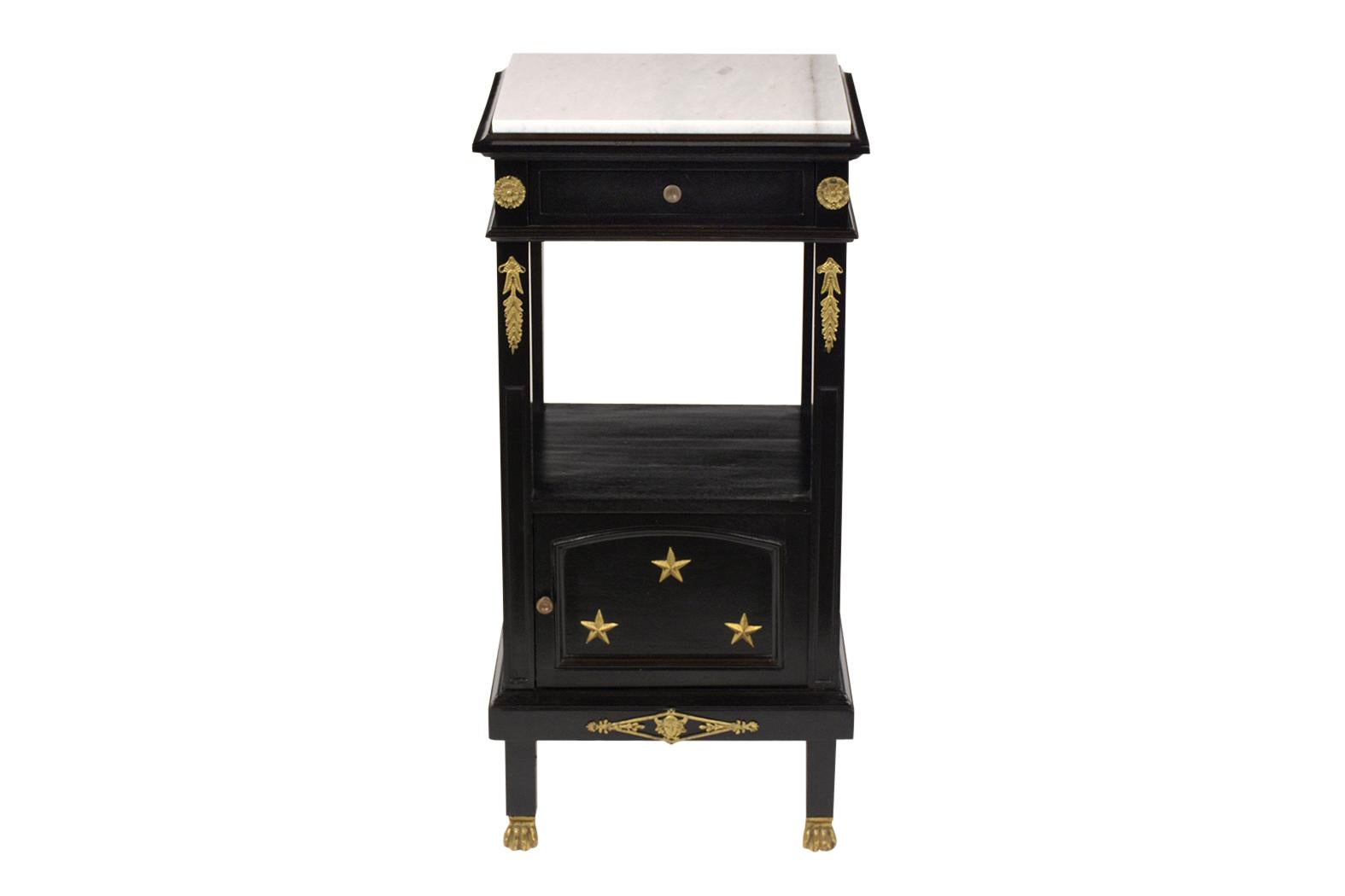 A French antique Empire style nightstand has been completed restored, features a newly black lacquered finish, and comes with a new Carrara marble top. The nightstand also has a single top drawer, a small open shelf in the center, and a door covered